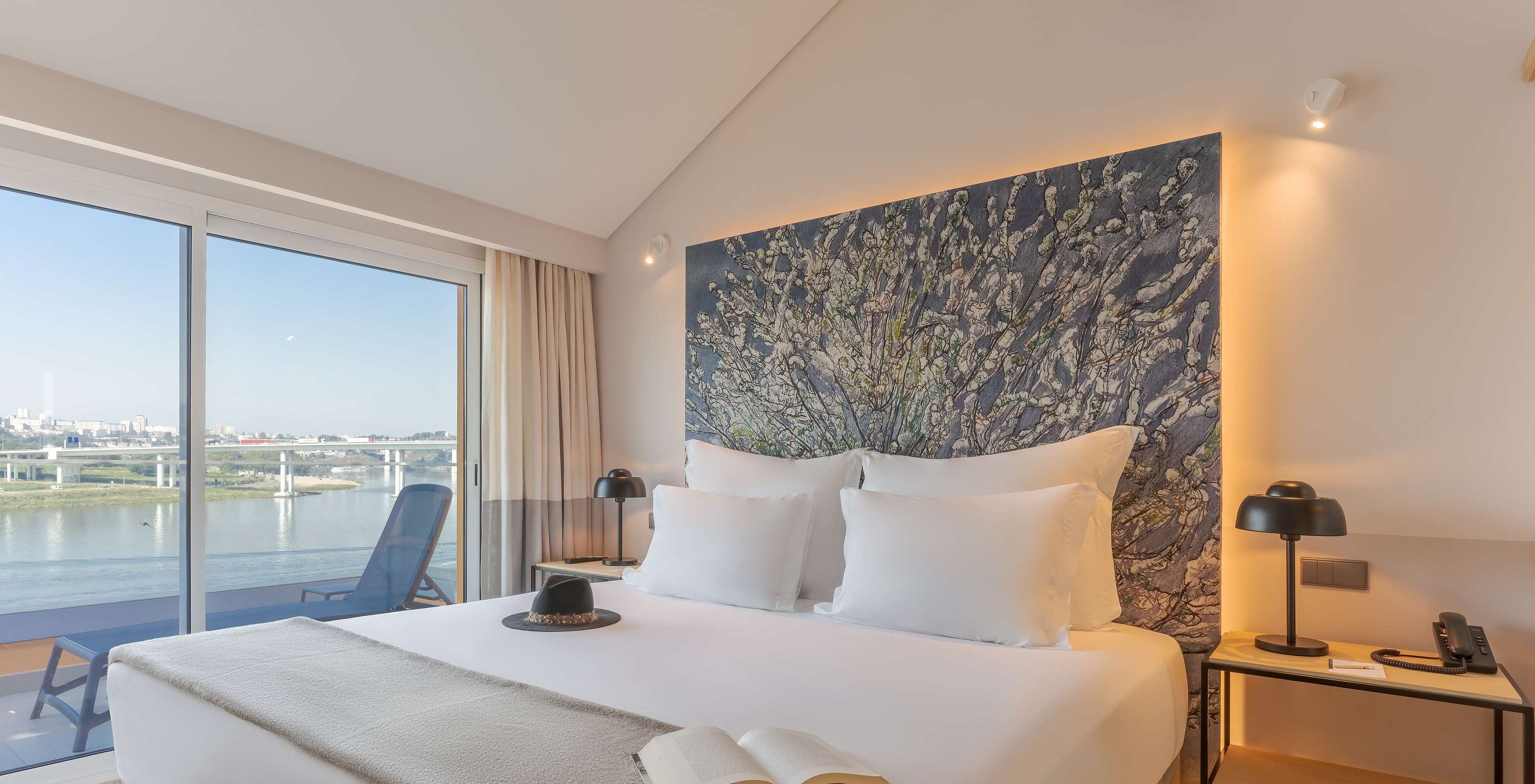 Die Suite Douro im Pestana Douro Riverside hat ein Doppelbett mit Nachttisch und Balkon mit Blick auf den Fluss