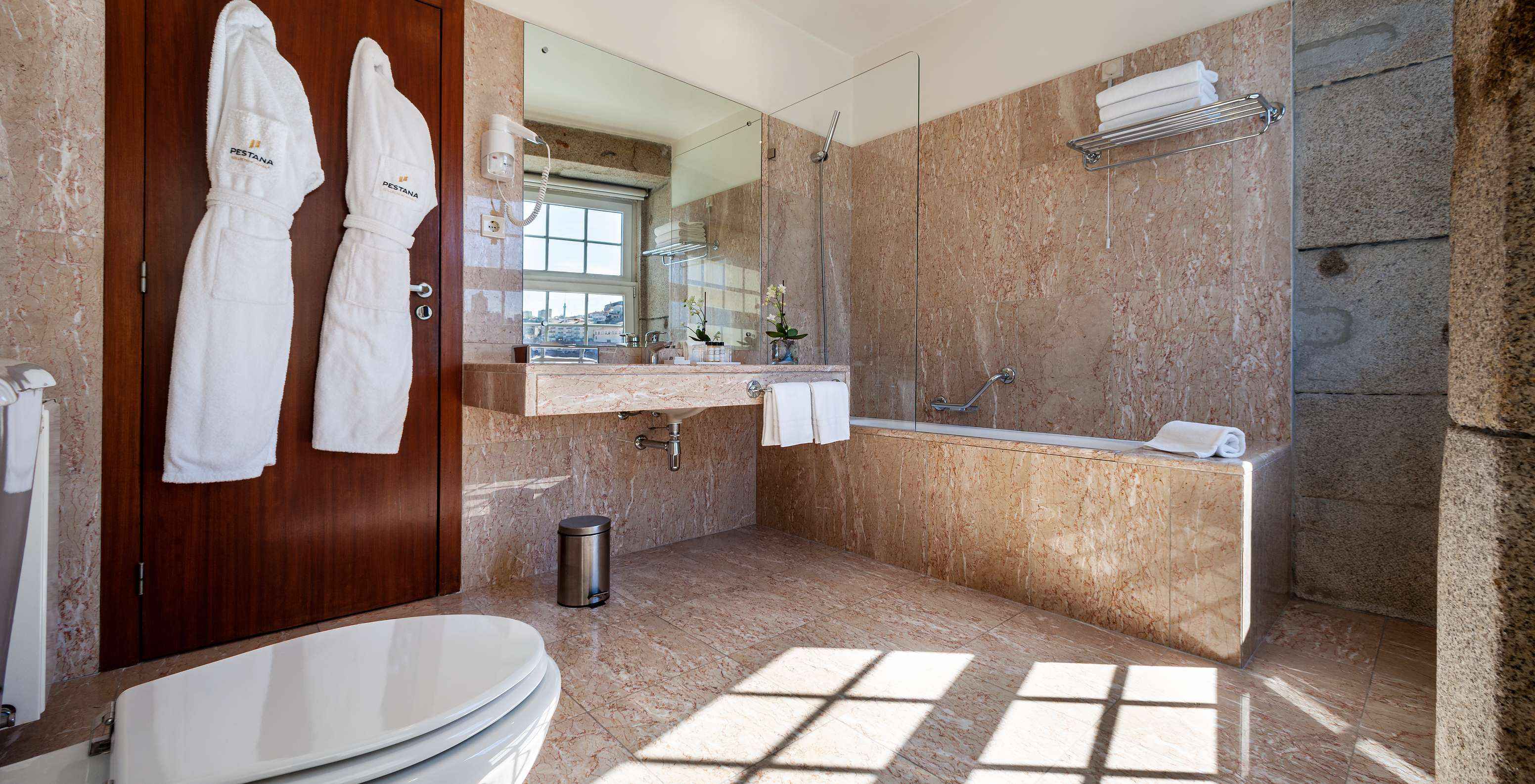 Plaza Pestana Vintage Porto hat ein Badezimmer mit Badewanne, zwei Bademänteln, Waschbecken und Haartrockner