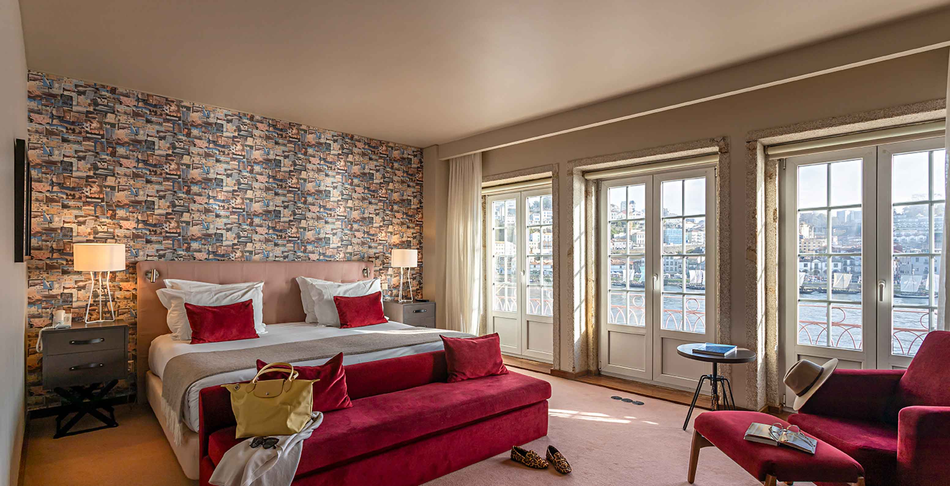 Die Suite Grand View des Pestana Vintage Porto verfügt über ein Doppelbett, ein rotes Sofa und Fenster mit Blick auf Porto
