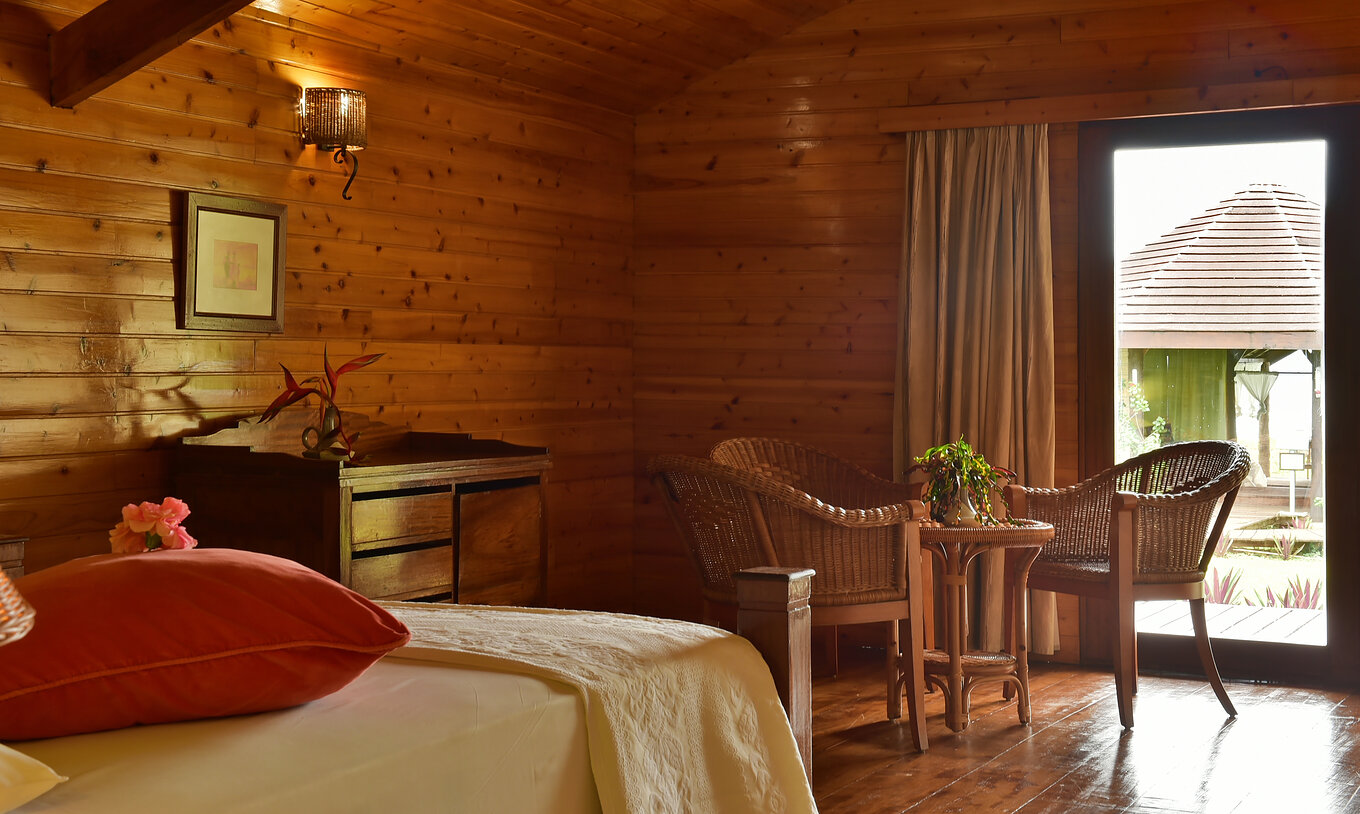 Das Doppelzimmer Superior im Pestana Equador hat Bett, Holzkommode und Tisch mit Stühlen