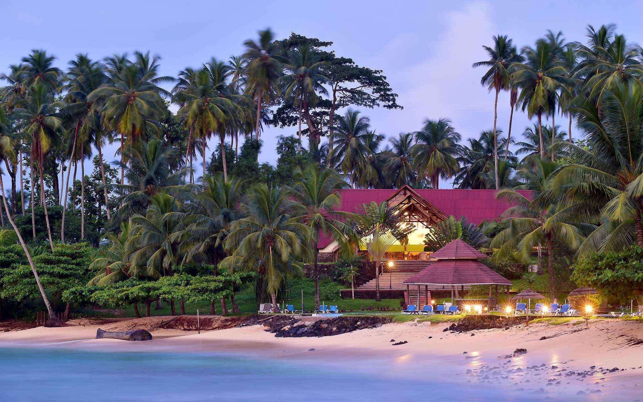 Strand und Gebäude mit Liegen und Palmen des Pestana Equador, Hotel auf Ilhéu das Rolas, São Tomé