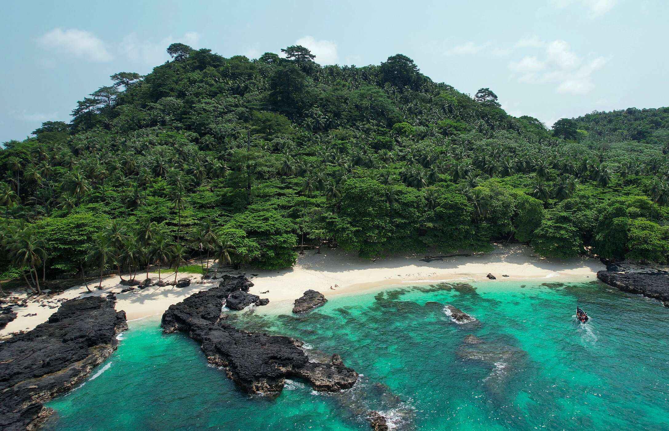 Praia Café, auf der Insel São Tomé, verlassen, mit Felsen sowohl am Strand als auch im Meer, und einer Wand aus Vegetation