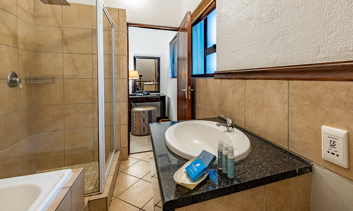 Das Familienzimmer im Pestana Kruger Lodge hat Bad mit Badewanne, Dusche, Waschbecken und Amenities