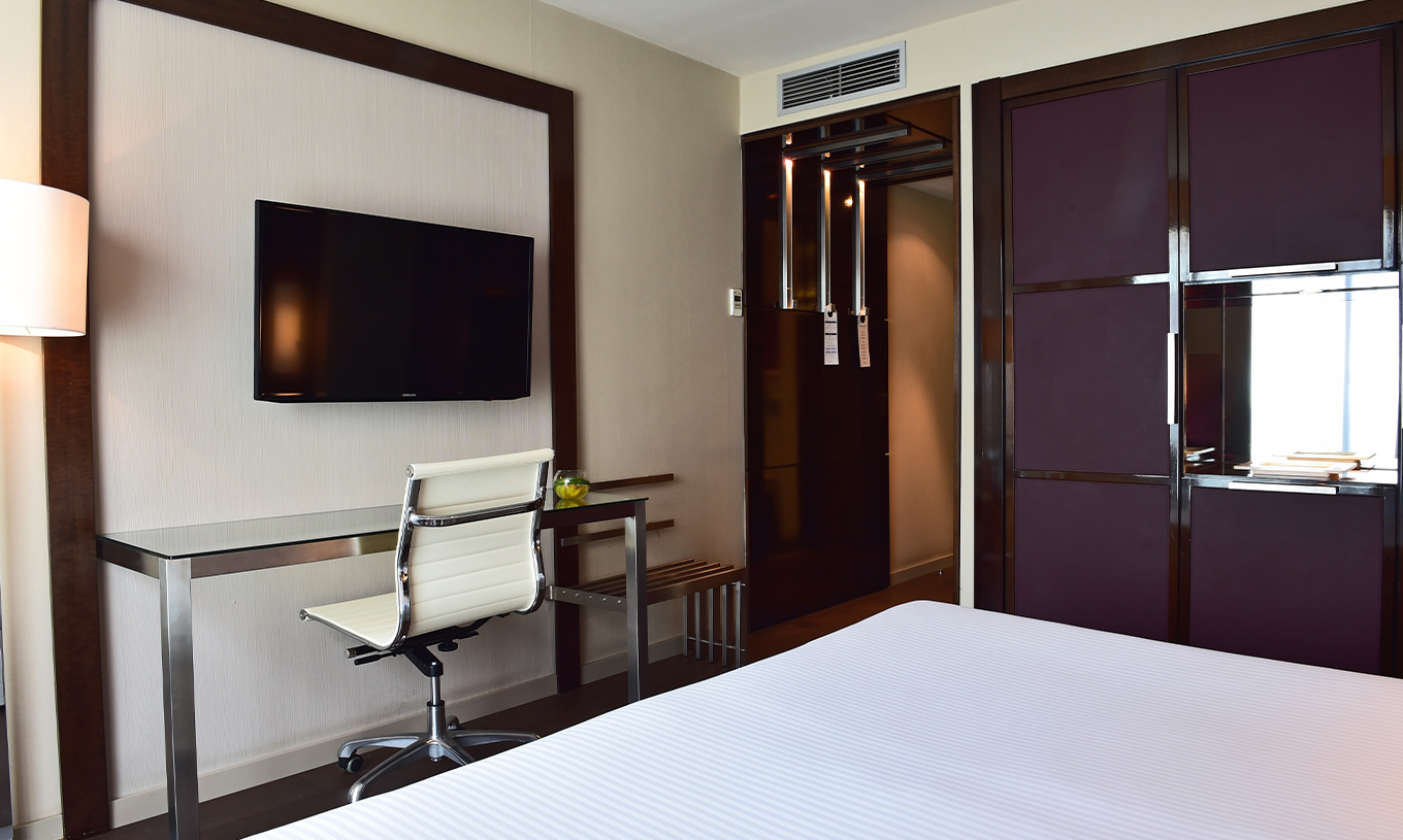 Das Premium Zimmer im Pestana Arena Barcelona hat einen Fernseher am Fuß des Bettes und einen lila Schrank