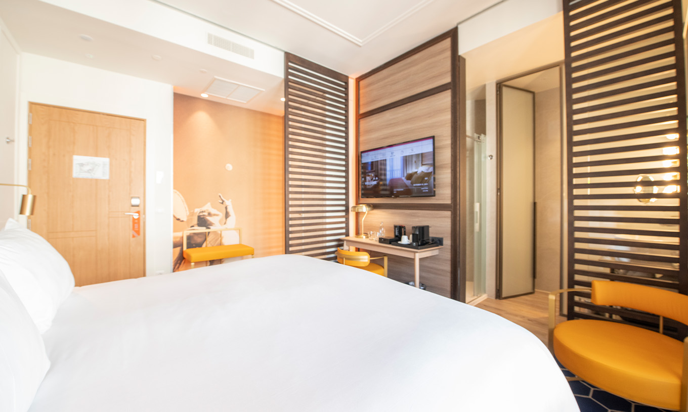 Das Legend Zimmer im Pestana CR7 Gran Vía Madrid hat ein Doppelbett, einen Stuhl, eine Lampe und zwei Bänke mit Trennwand