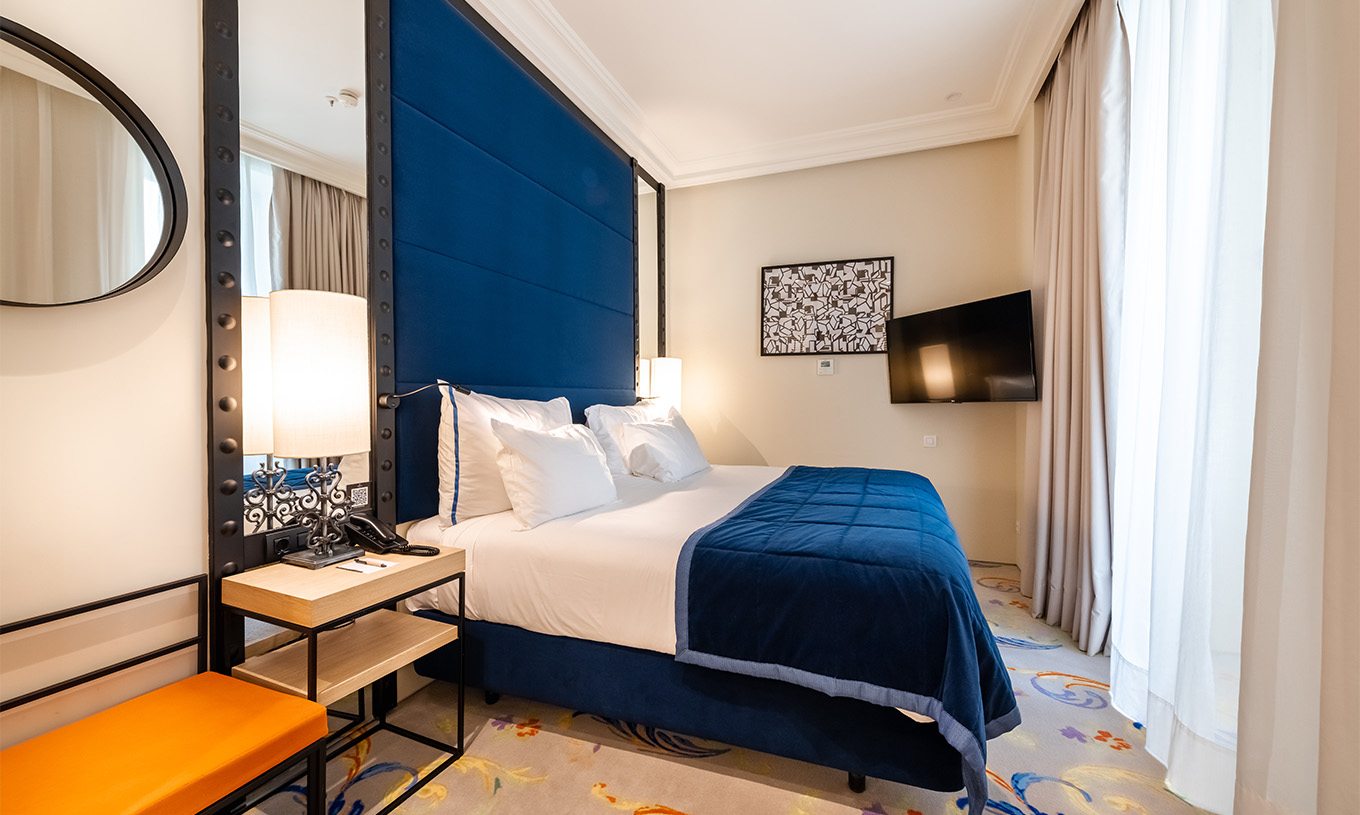 Die Suite im Pestana Plaza Mayor Madrid hat ein Doppelbett, Nachttisch, Fernseher an der Wand und ein Fenster