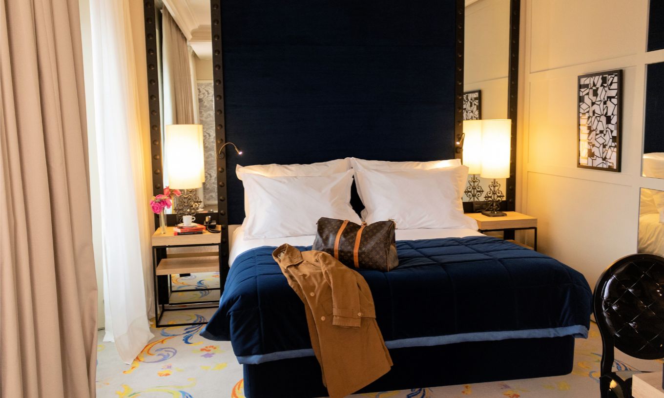 Das Superior Plus Zimmer im Pestana Plaza Mayor Madrid hat ein Doppelbett mit einem Koffer und einem Mantel auf dem Bett.