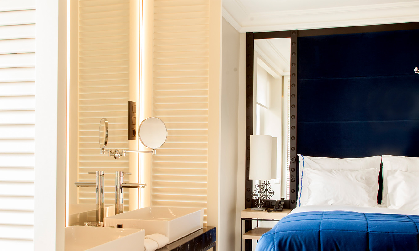 Das Superior Zimmer im Pestana Plaza Mayor Madrid hat ein Doppelbett mit blauer Kopfstütze und Waschbecken