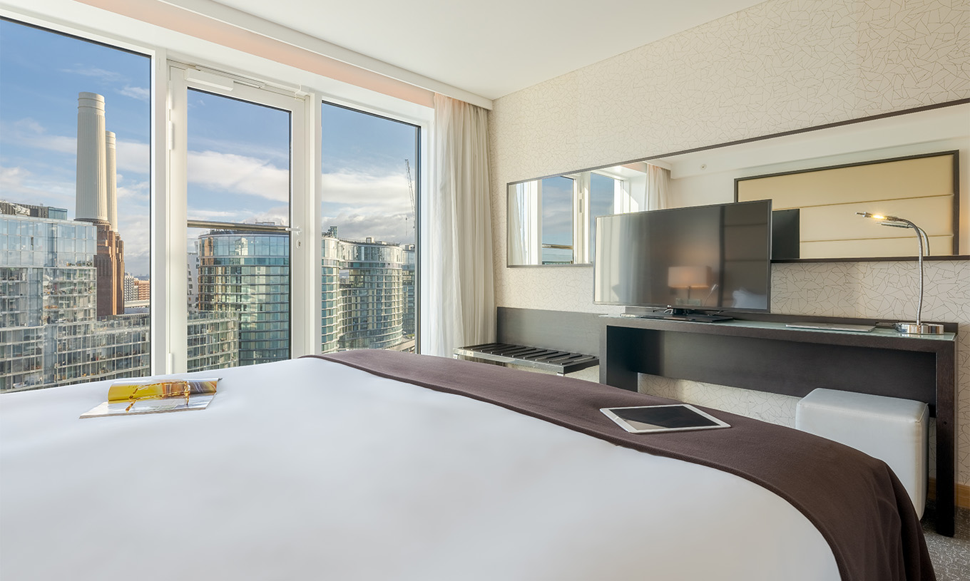Die Signature Suite im Pestana Chelsea Bridge hat ein Doppelbett, Schreibtisch mit Fernseher und Blick auf die Stadt