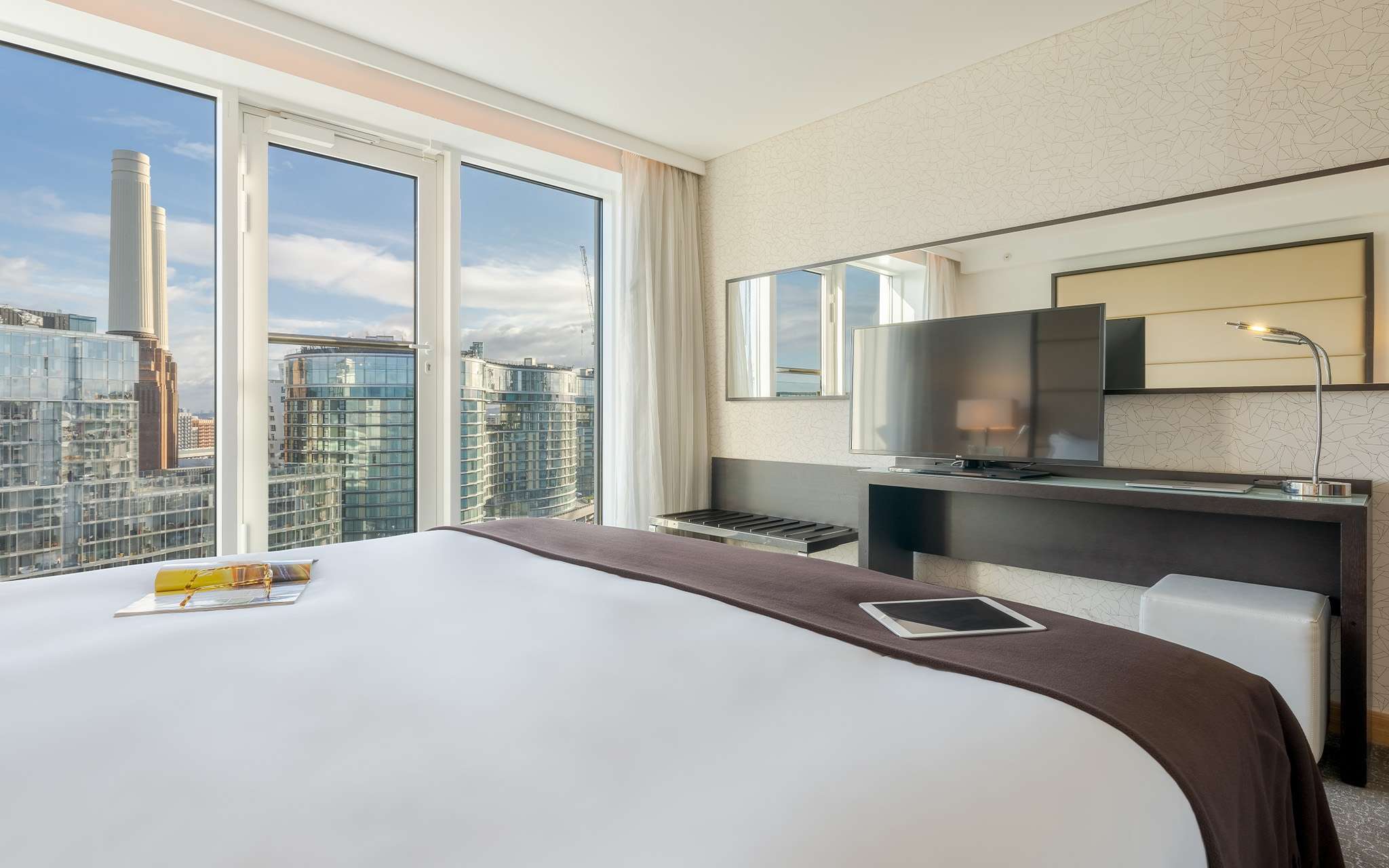 Zimmer mit Doppelbett, Fernseher, Spiegel und großen Fenstern mit Blick auf London