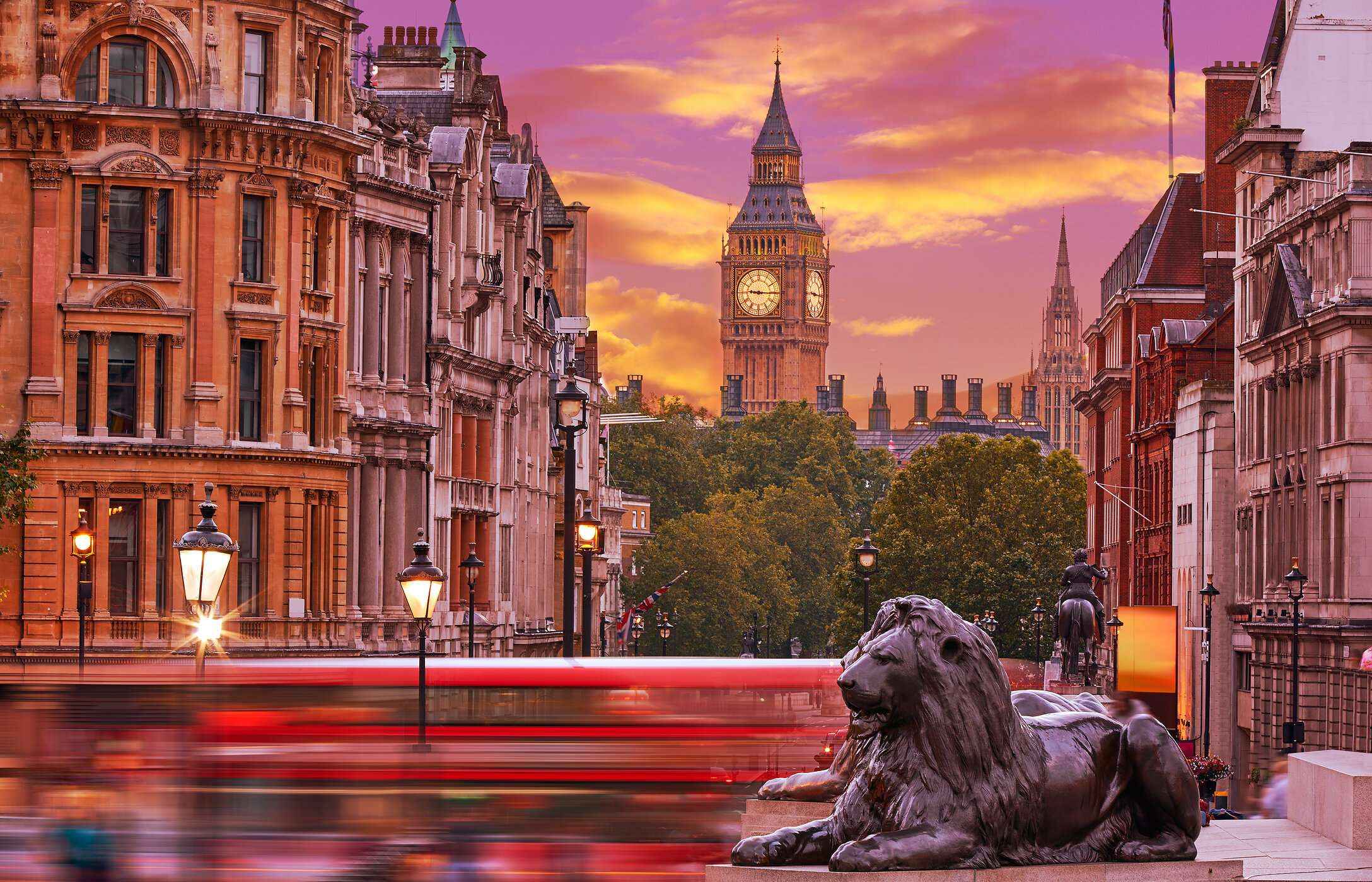 Busbetrieb am Trafalgar Square in London, mit einer Löwenstatue im Vordergrund und dem Big Ben im Hintergrund.