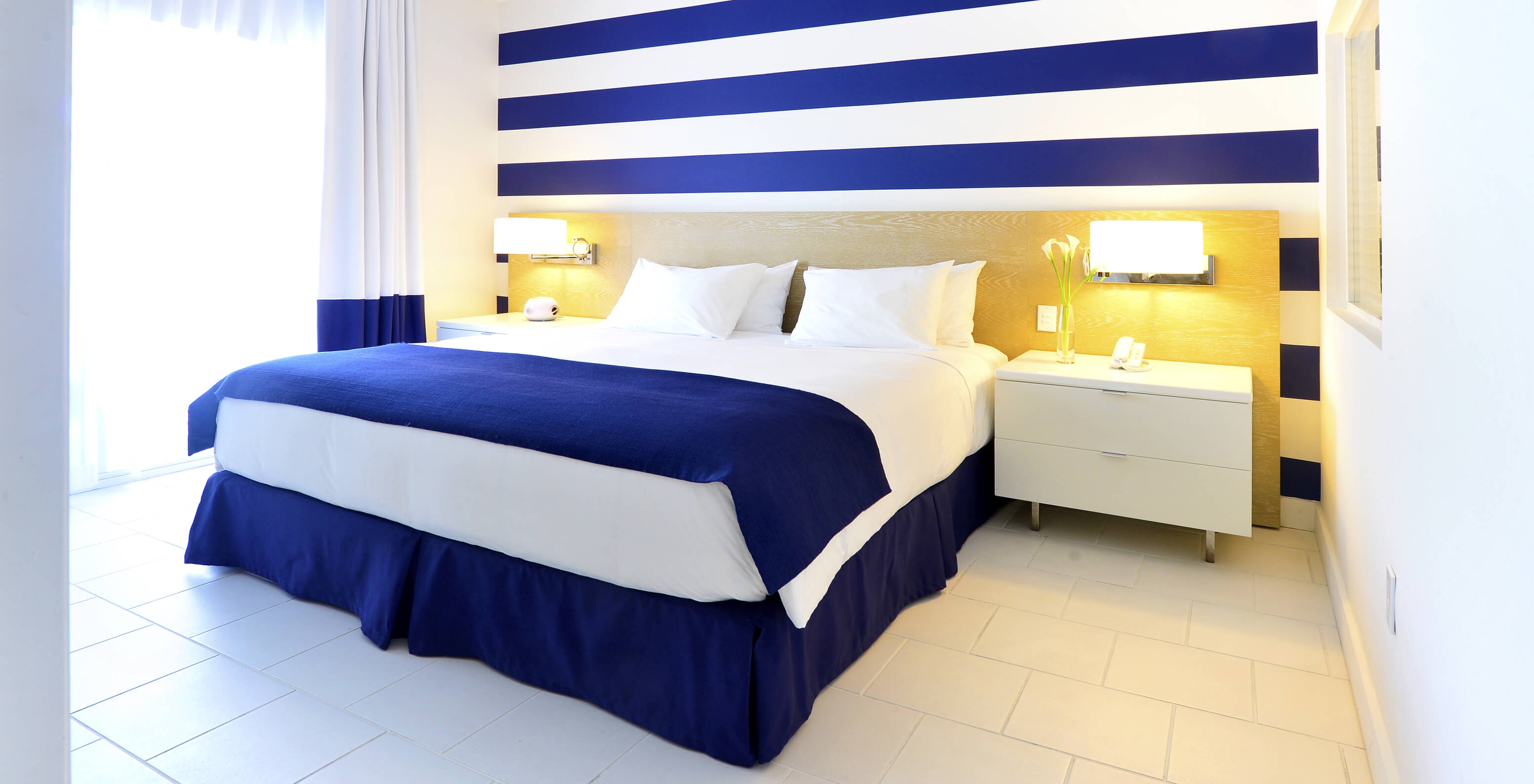 Die Suite King mit Balkon im Pestana Miami South Beach hat Doppelbett, Nachttisch und Lampe