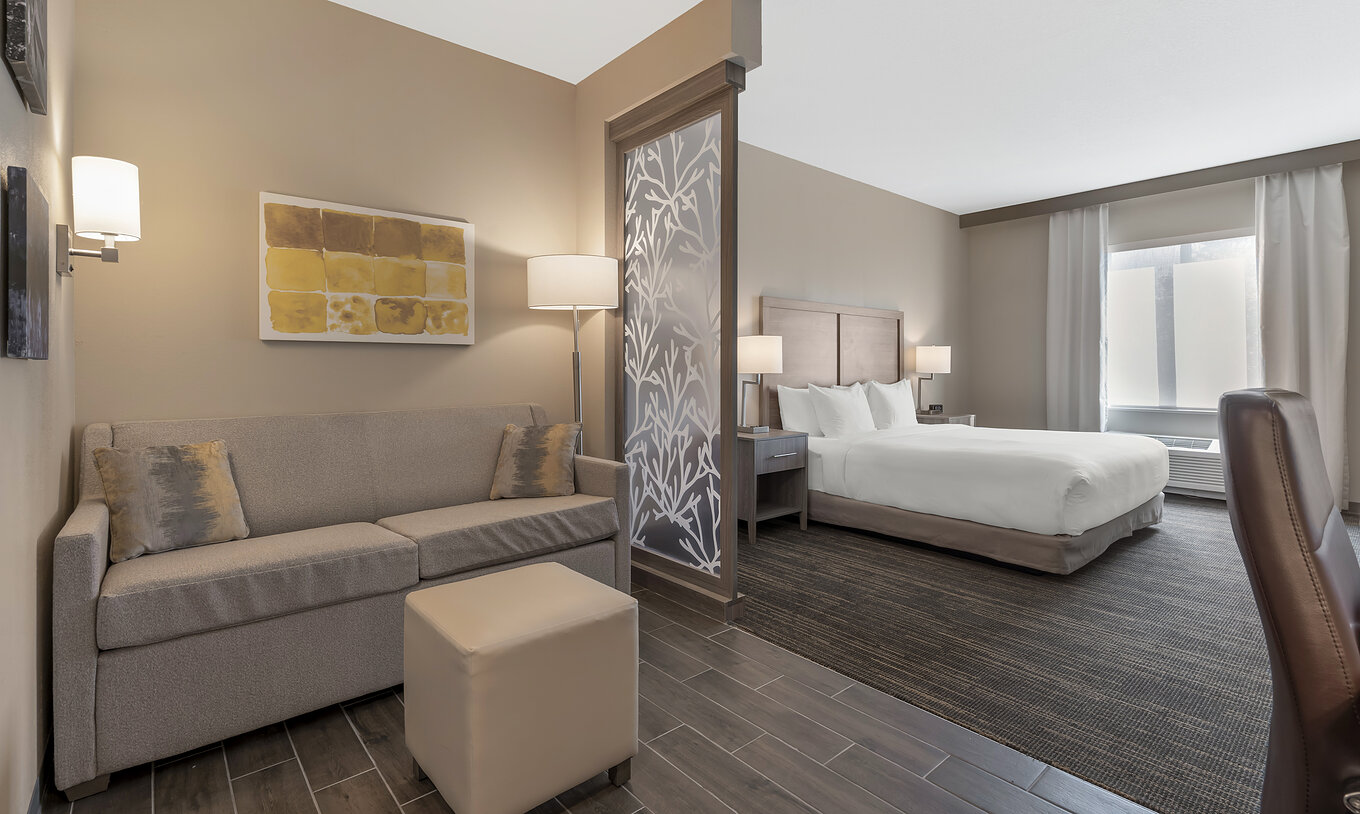 Die ADA King-Suite im Pestana Orlando Suites Lake Buena Vista hat ein Doppelbett, Nachttisch, Sofa und Lampe