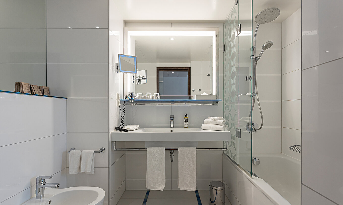 Deluxe room at Pestana Berlin Tiergarten has a bathroom with bathtub and shower, a sink, and a mirror