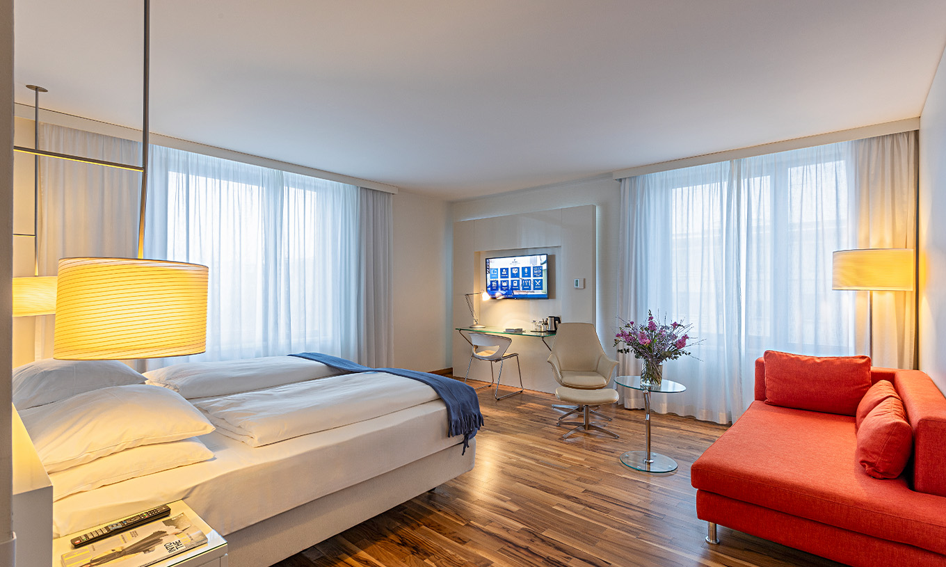 Grand Deluxe room at Pestana Berlin Tiergarten has a double bed, TV, sofa, armchair and desk