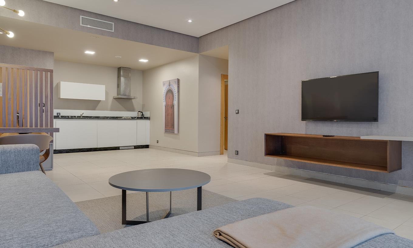 The Family Suite at Pestana Casablanca has a spacious living room with a sofa, satellite TV, dining table, and kitchenette