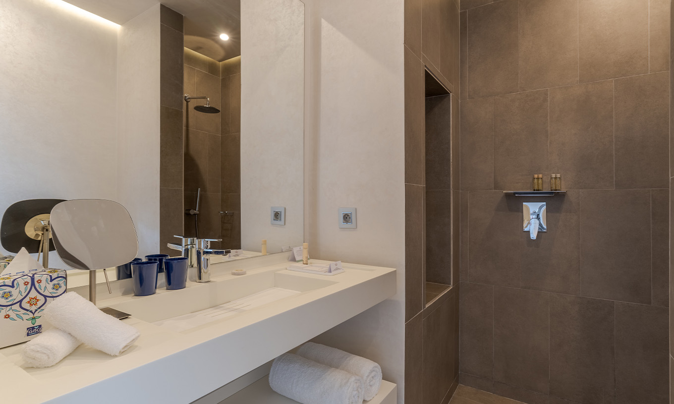 The CR7 Suite at Pestana CR7 Marrakech has a bathroom with a walk-in shower and a sink with a large mirror