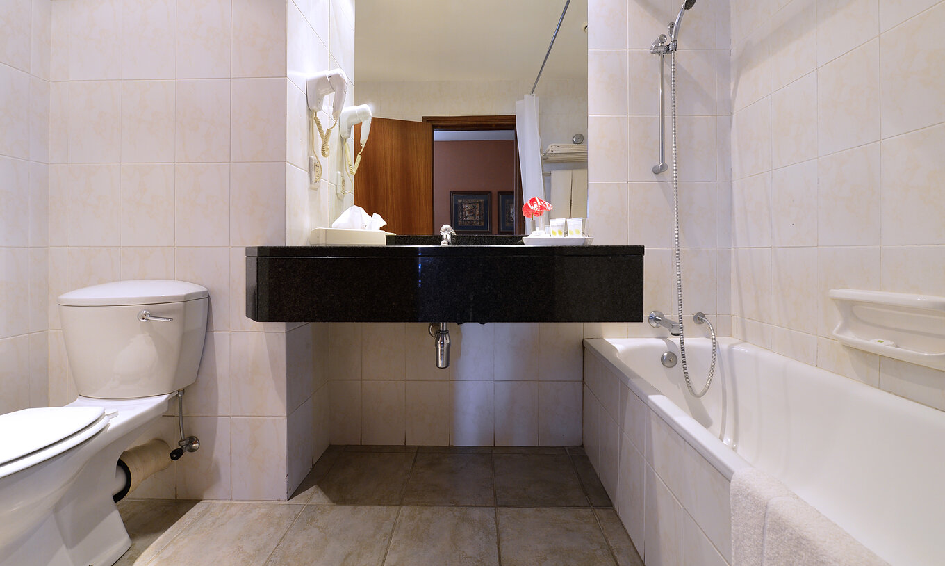 The Family Executive Suite of Pestana Rovuma has a bathroom with bathtub with shower, sink with mirror, and a toilet