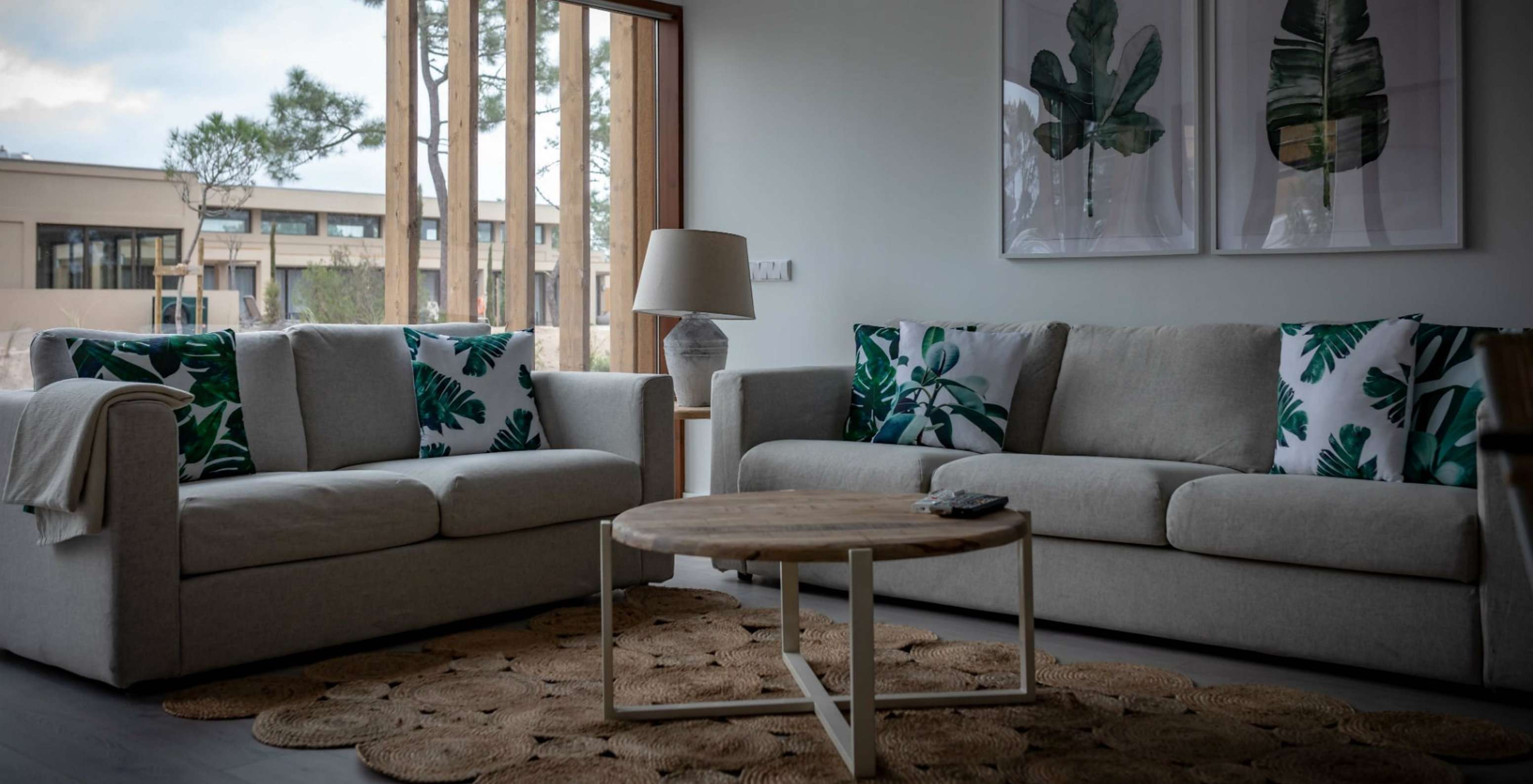 The Eco Village Apartment Ground Floor of Pestana Tróia Eco Resort has a room with two sofas, a table, and a leaf picture