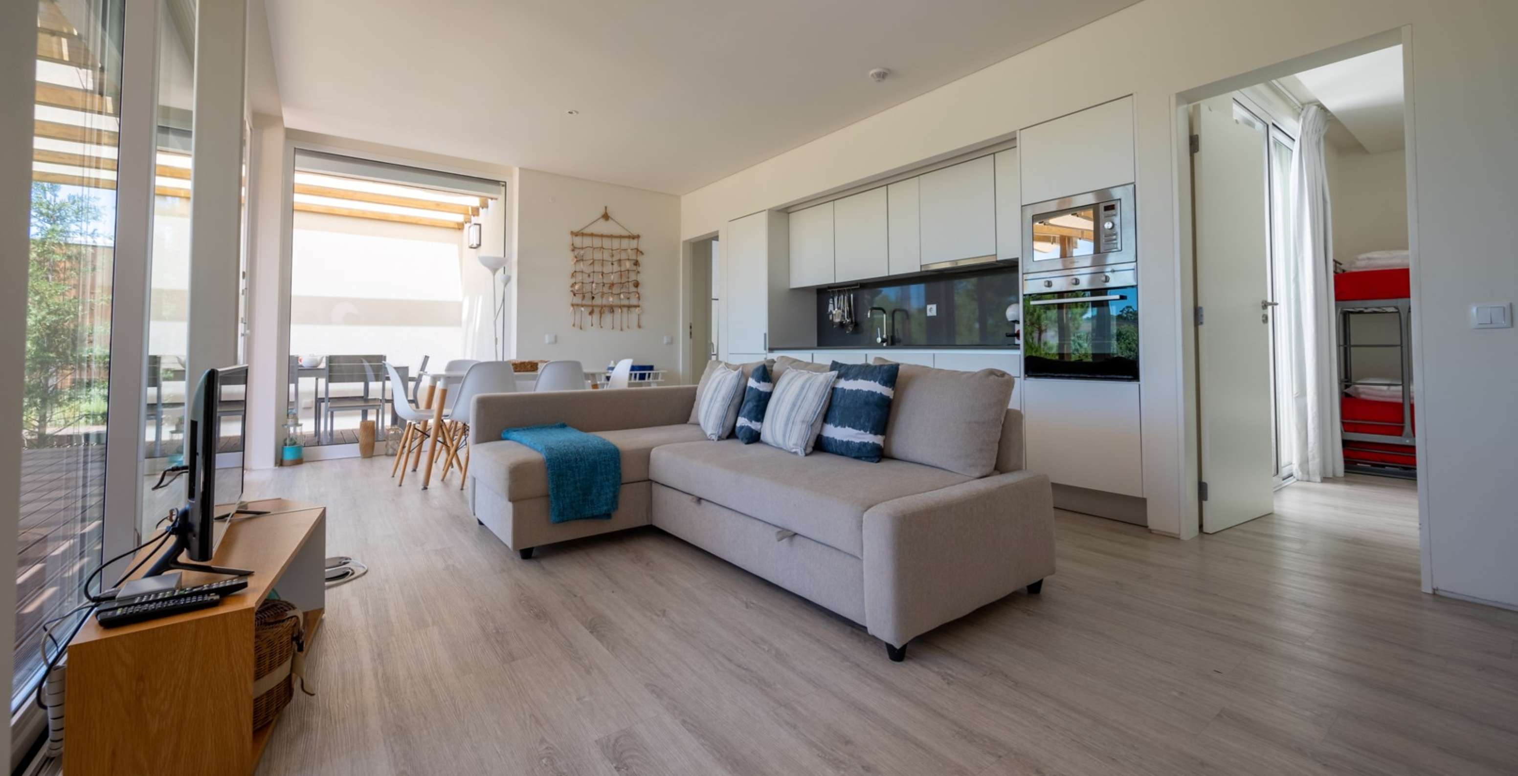 The Green Villa with Private Pool of Pestana Tróia Eco Resort has a room with a kitchen, sofa, table, and television