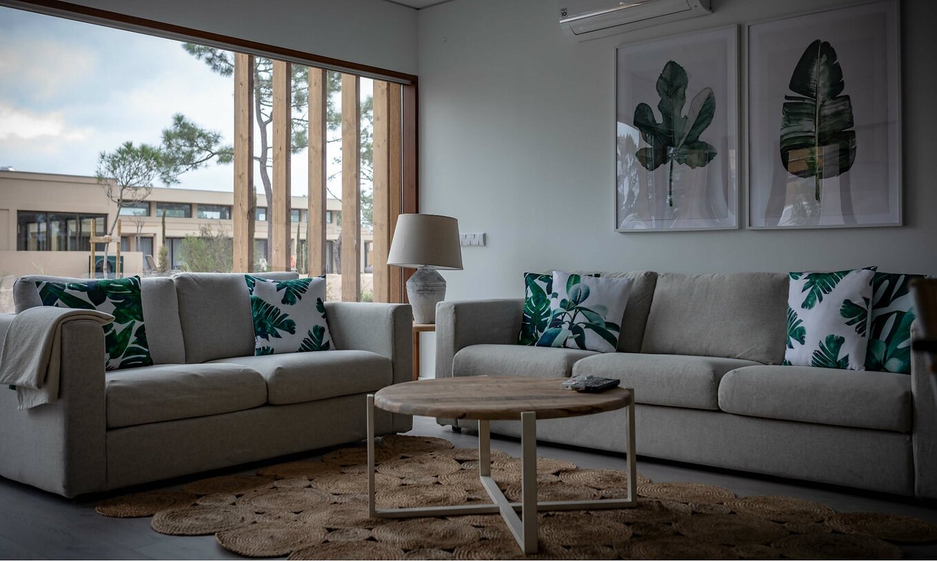 The Eco Village Apartment Ground Floor of Pestana Tróia Eco Resort has a room with two sofas, a table, and a leaf picture