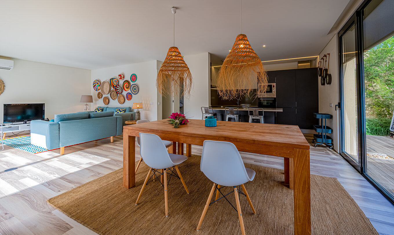 The Pine Villas of Pestana Tróia Eco Resort have a room with a wooden table, lamps, and a kitchen