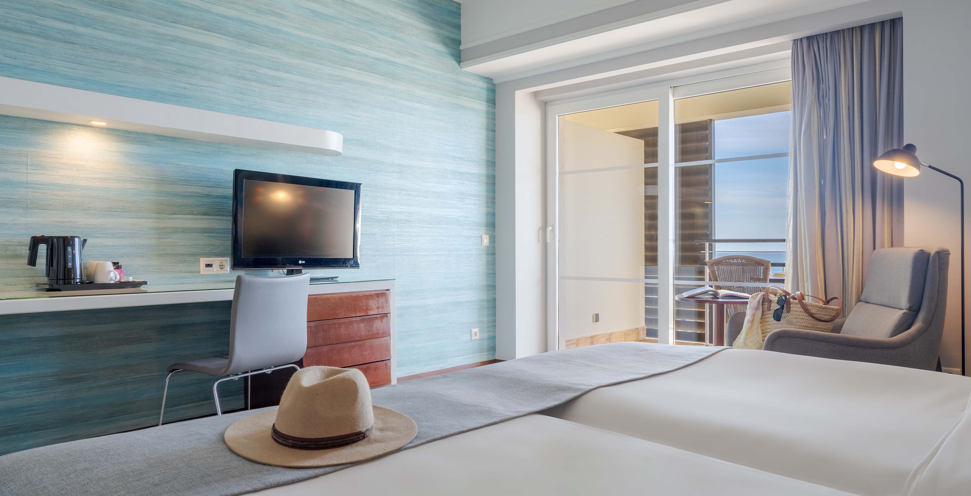 The Superior Sea View at Pestana Alvor Praia has two joined beds with an armchair, desk, TV, and sea view