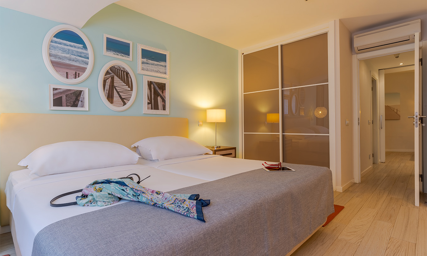 The Duplex Sea View Suite T2 at Pestana Alvor Praia has two joined beds, a wardrobe, and wall art