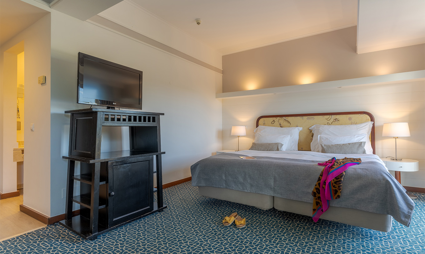The Superior at Pestana Alvor Praia has two joined beds with a headboard, a black unit with TV, and a rug