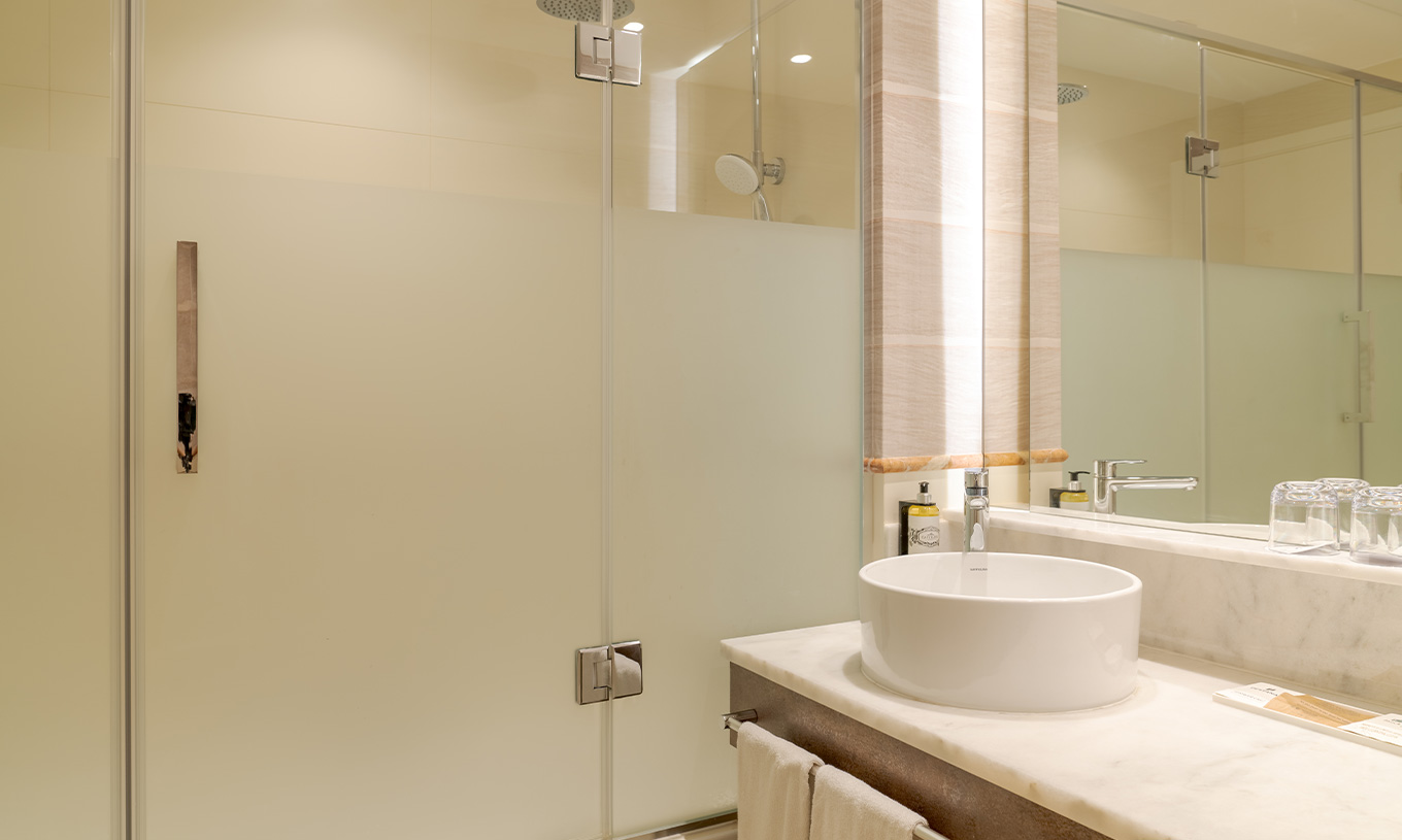 The Family Room at Pestana Blue Alvor Beach has a bathroom with a sink, mirror, towels, and a shower