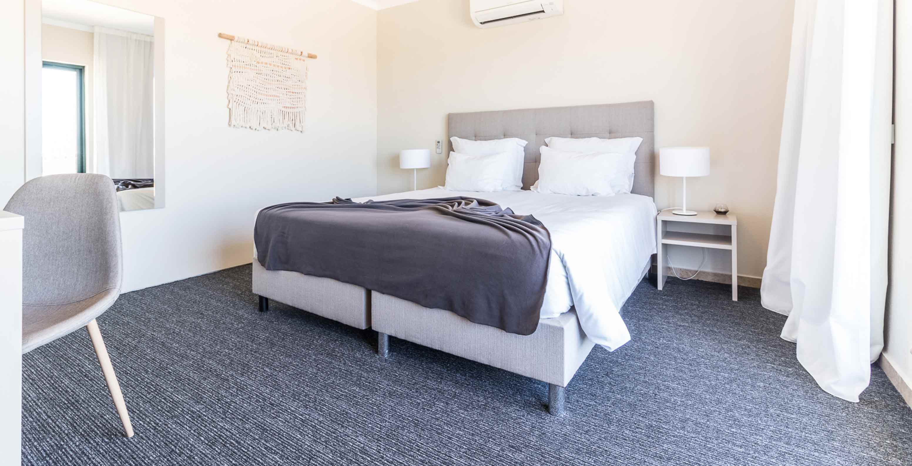 The two-bedroom apartment at Pestana Gramacho has a modern bedroom with bed, AC and minimalist decor