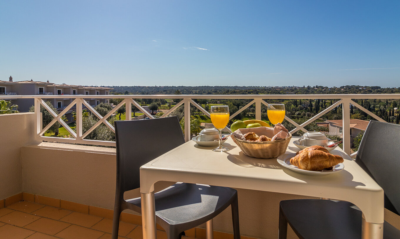 The one-bedroom apartment at Pestana Gramacho has an outdoor table in a sunny, green and cozy setting