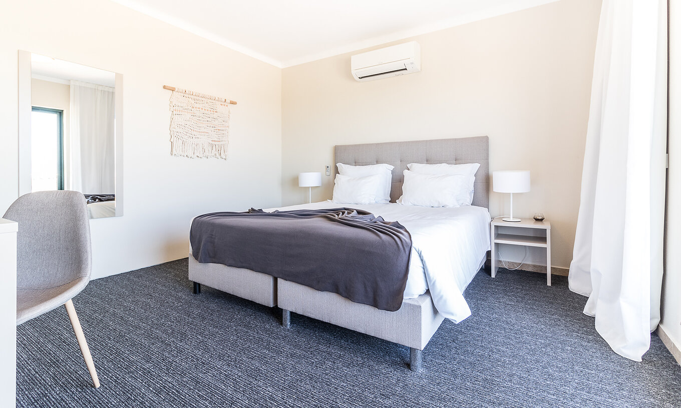 The two-bedroom apartment at Pestana Gramacho has a modern bedroom with bed, AC and minimalist decor
