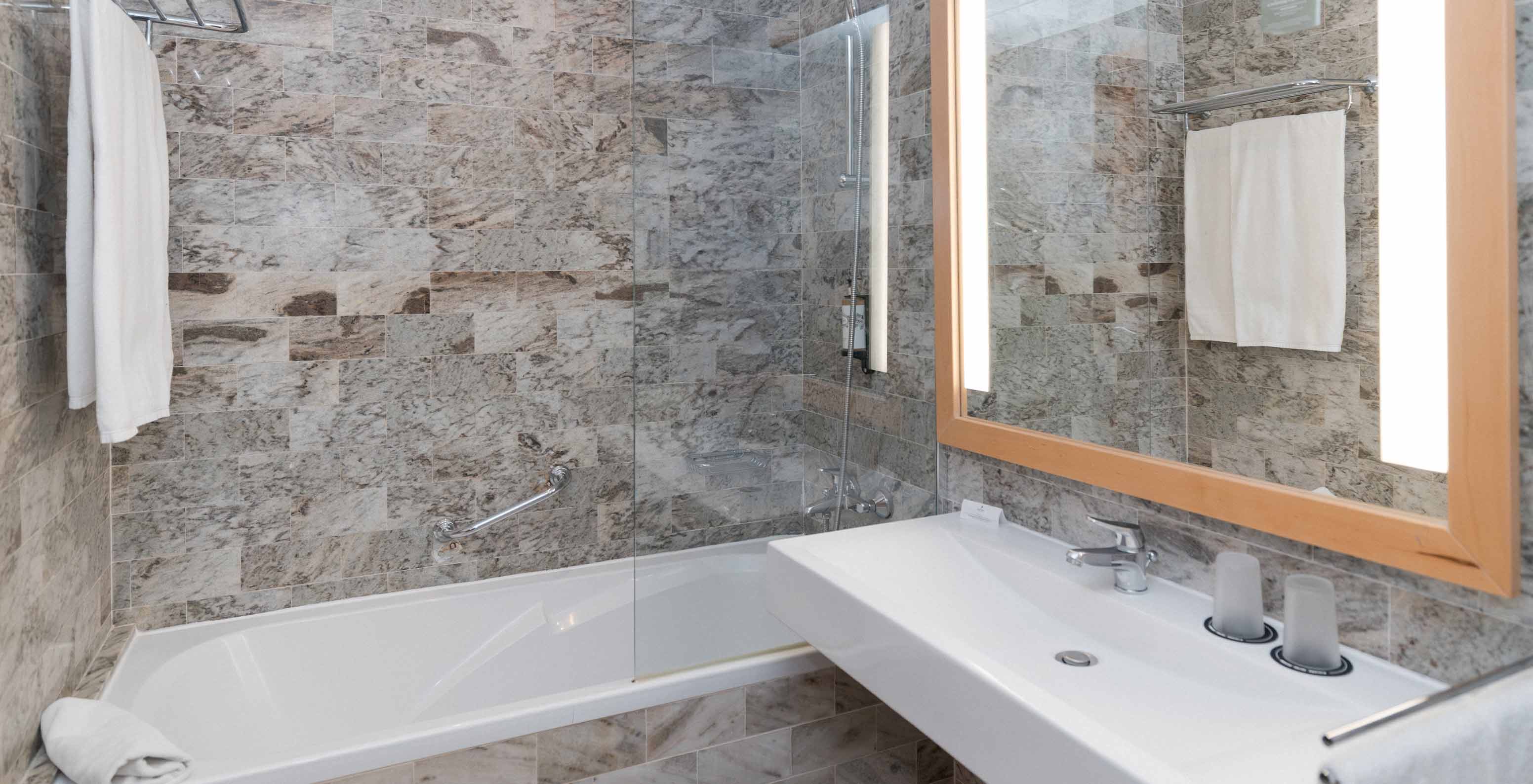 The Superior Sea View Suite at Pestana Viking has a bathroom with sink, large mirror and bathtub with shower