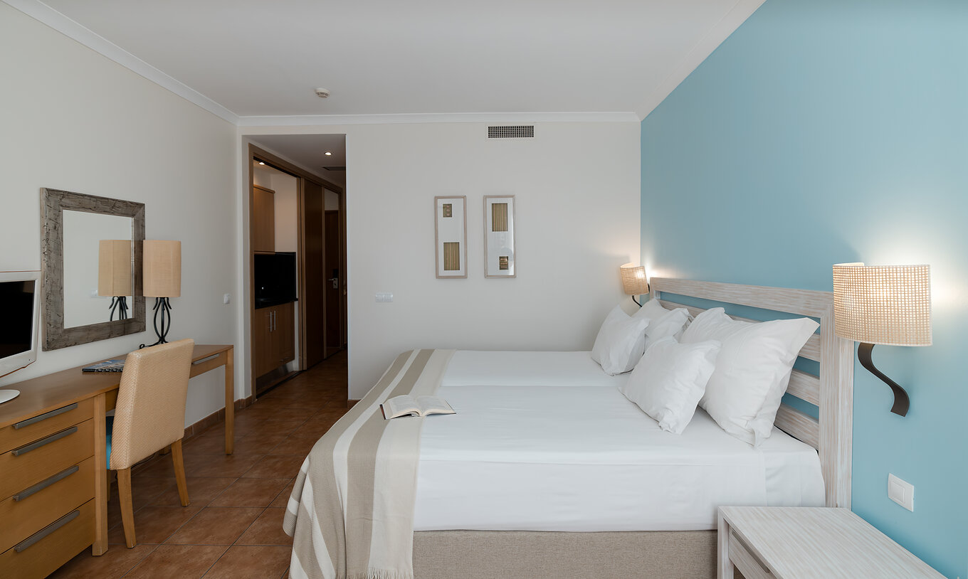 The Deluxe Sea View at Pestana Viking has two beds, bedside table and desk with chair