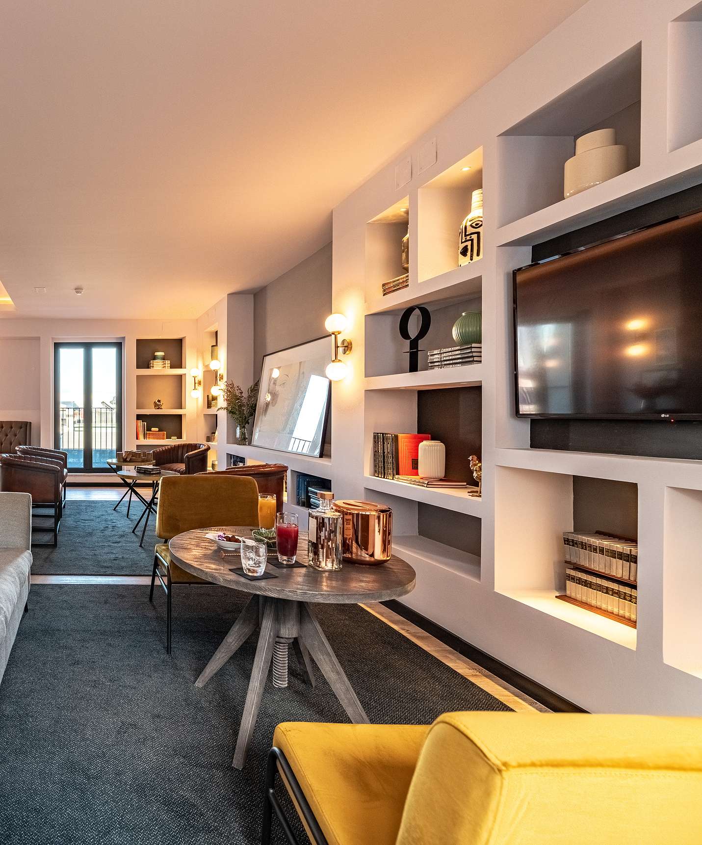 Lounge with sofas, chairs, tables, pictures, television, rugs, and decor items with windows overlooking the city