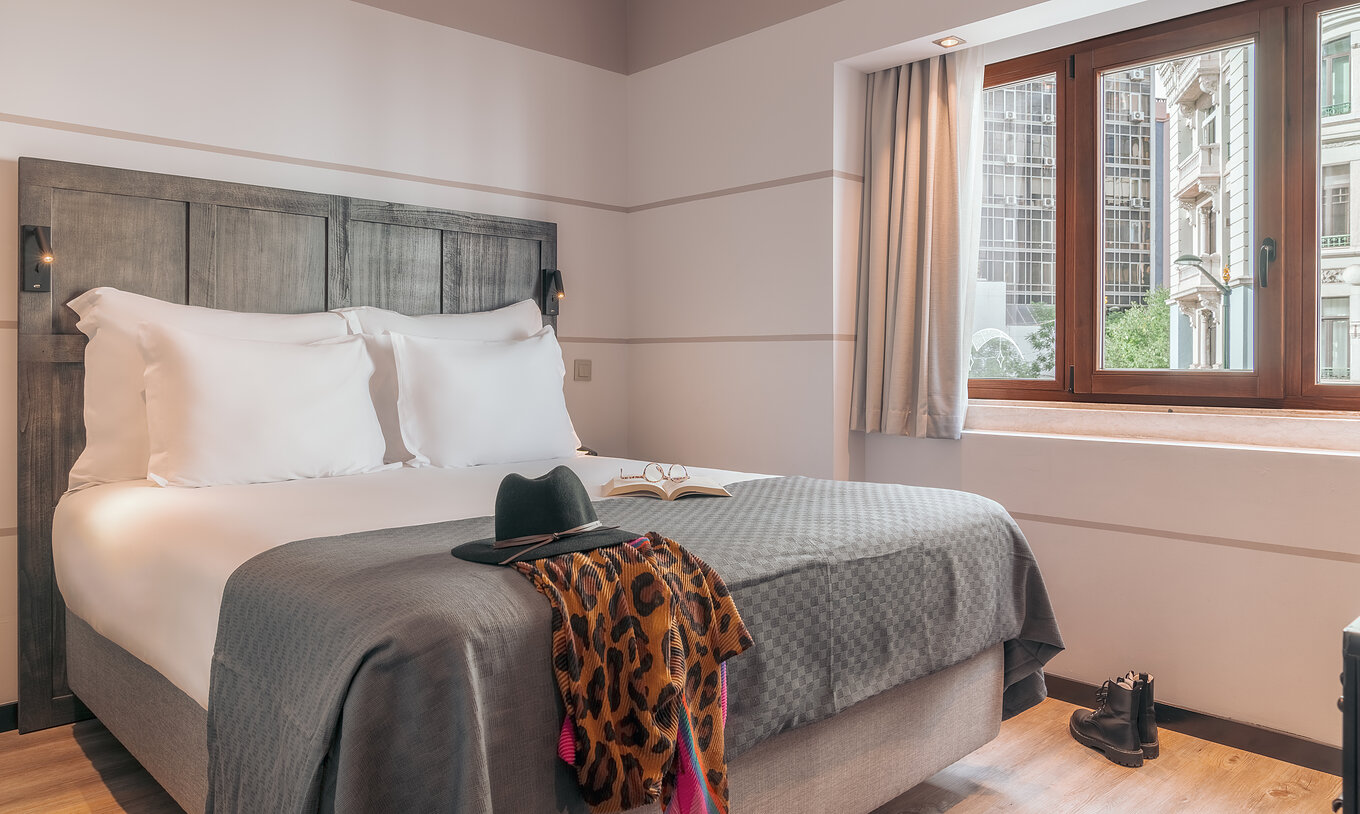 The Vintage Room at Pestana Lisboa Vintage has a double bed with headboard and gray blanket, boots on wooden floor