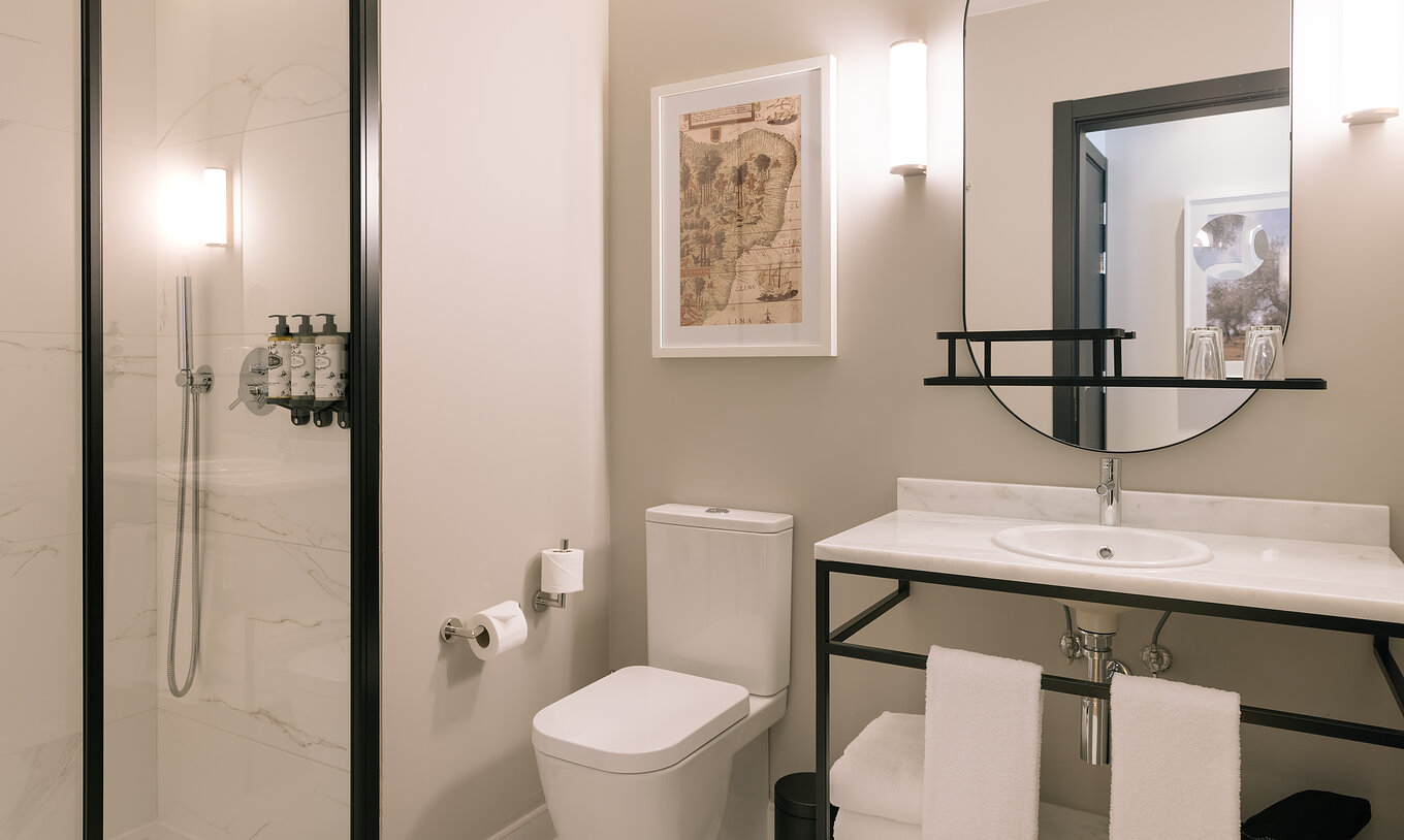 The Family Suite of Pestana Rua Augusta Lisboa has a bathroom with sink, mirror, toilet, white towels, and shower