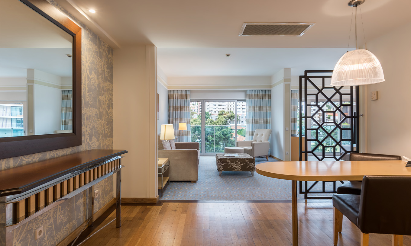 The Family Double Room at Pestana Carlton Madeira has a large entrance with a table and chairs, a mirror, and sofas