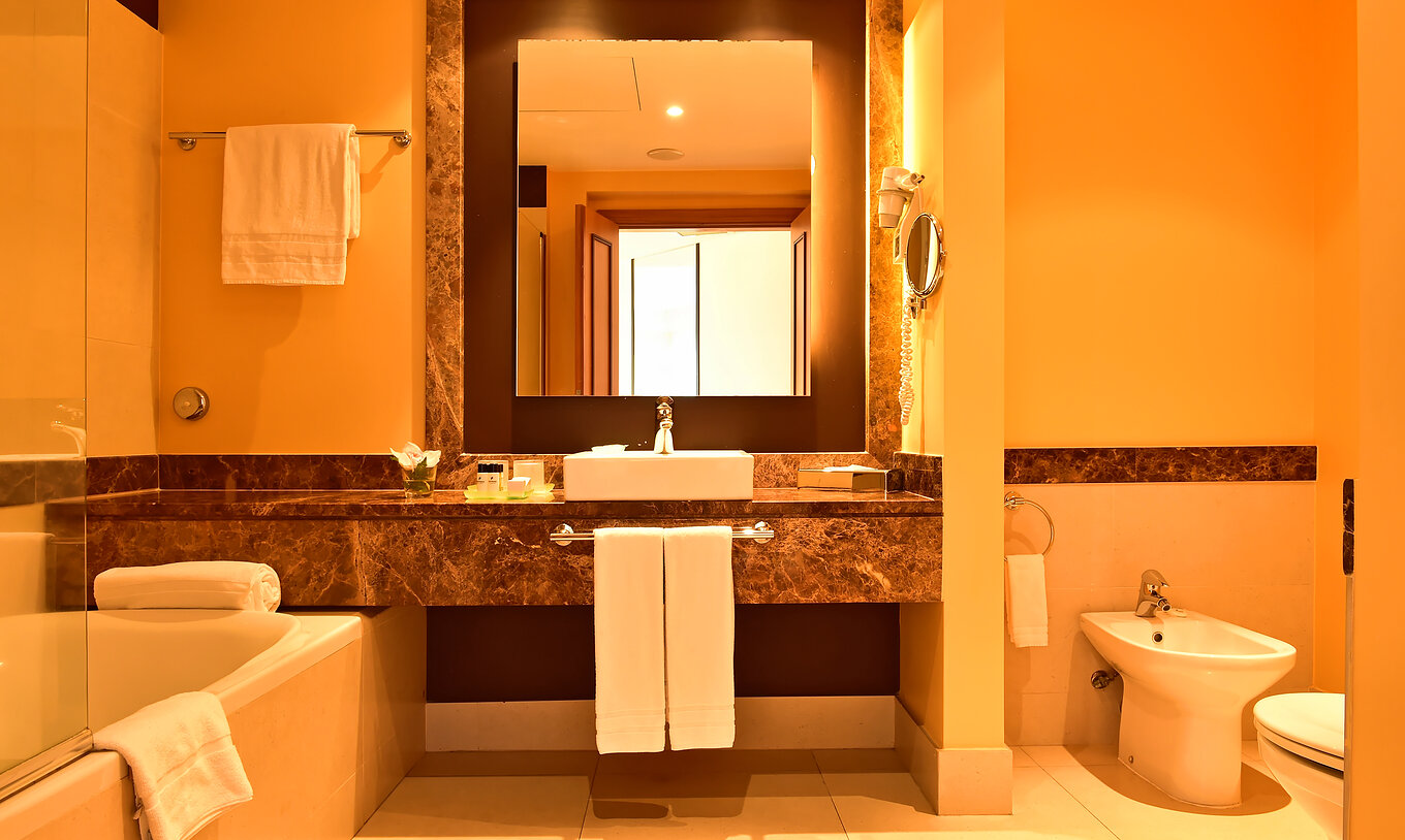 The Junior Suite of Pestana Promenade has a bathroom with bathtub, sink, and a square mirror