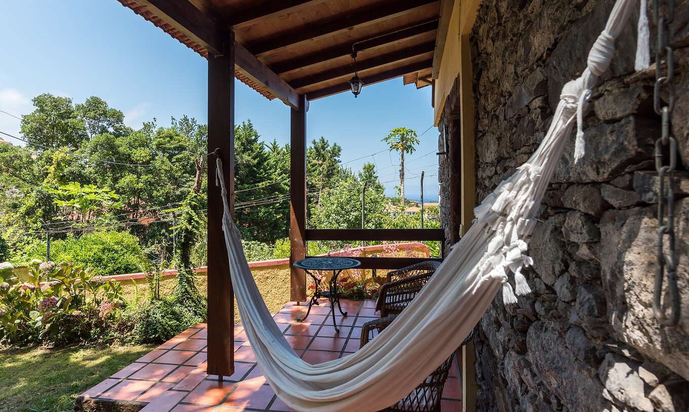 The Villas of Pestana Quinta do Arco have a hammock on the balcony, with chairs and a side table, and a view of the garden