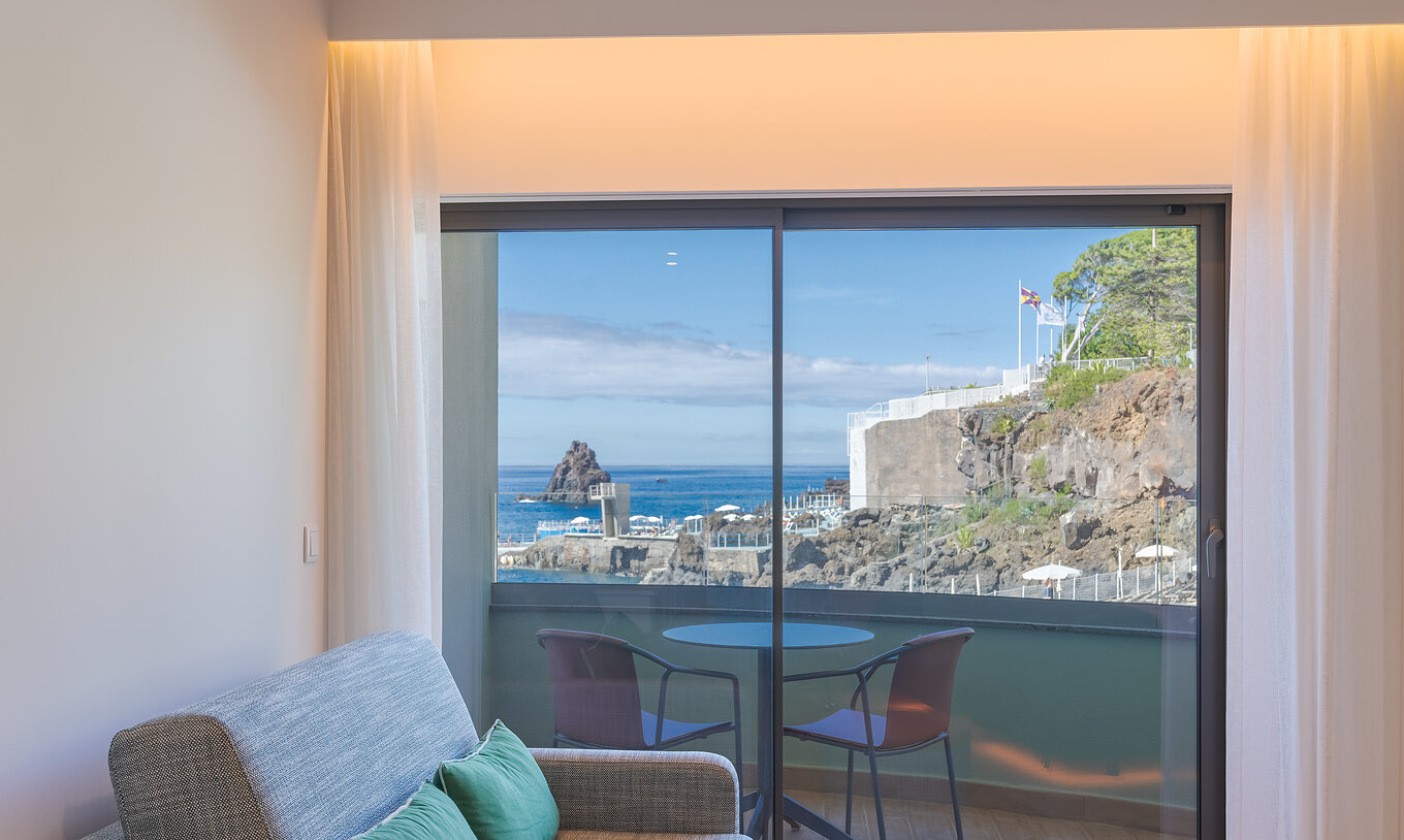 The Classic Lateral Sea View room at Pestana Vila Lido Madeira features a sofa next to the balcony with lateral sea view