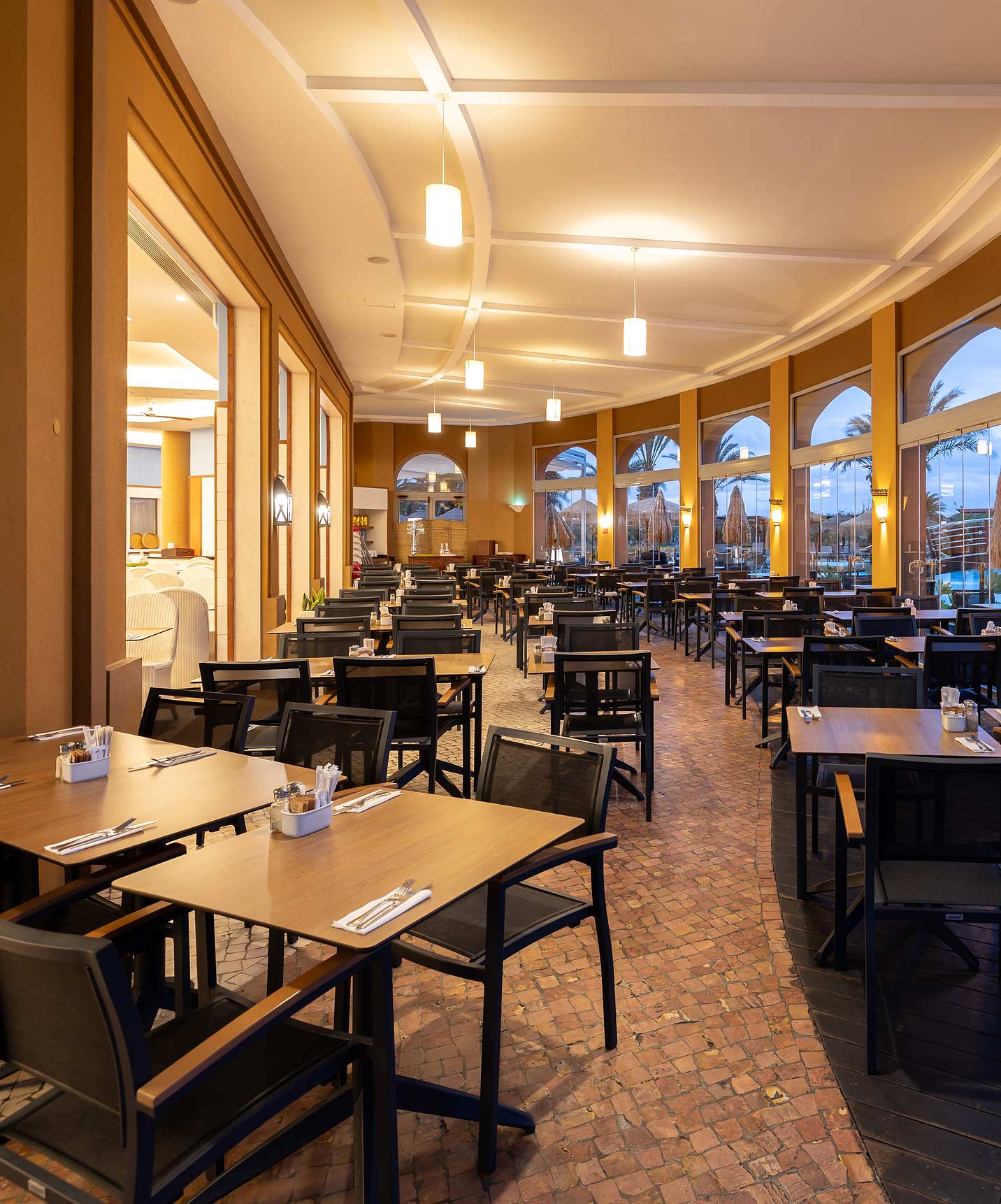 Informal dining room at Pestana Porto Santo All Inclusive with several square tables and chairs