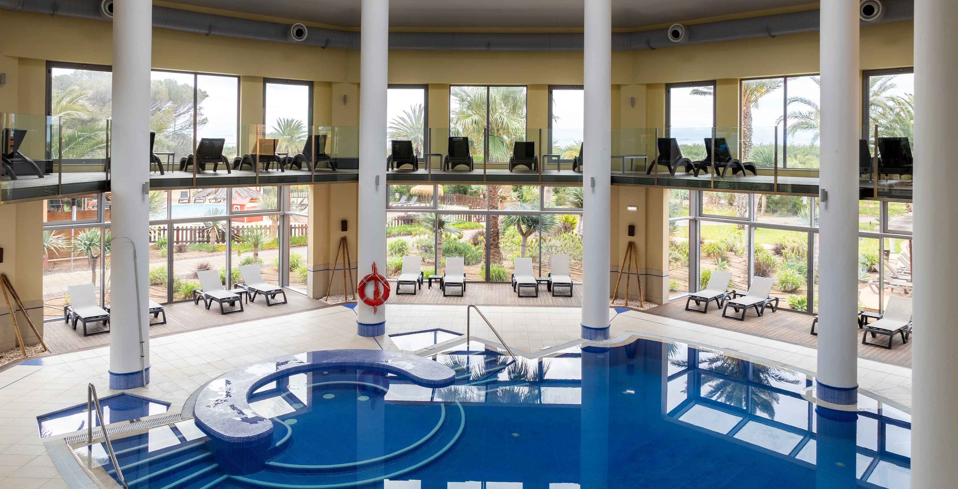 Large indoor pool at Pestana Porto Santo, with several sun loungers and a view of the garden