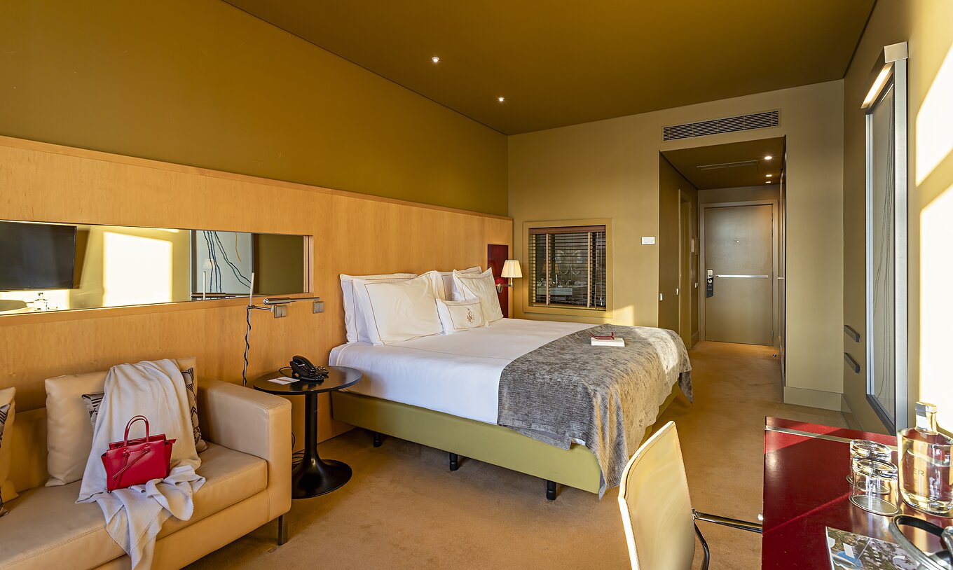 The Executive Superior has a double bed, a sofa, and a red desk