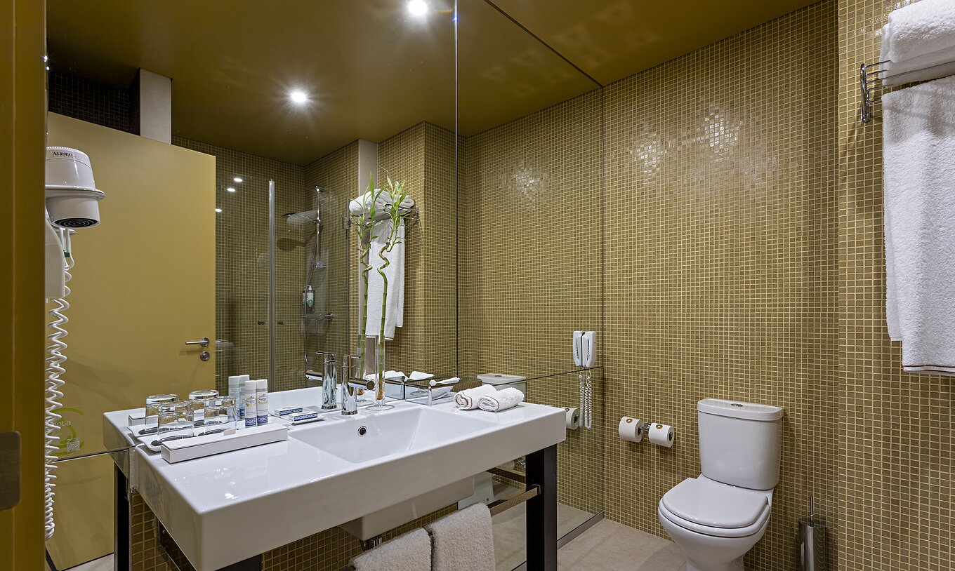 Pestana Palácio do Freixo’s Loft Attic has a bathroom with yellow tiles, toilet and washbasin