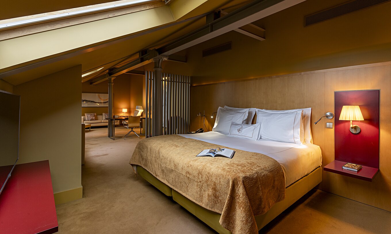 Pestana Palácio do Freixo’s Loft Attic is in the attic, with a double bed and yellow bedspread