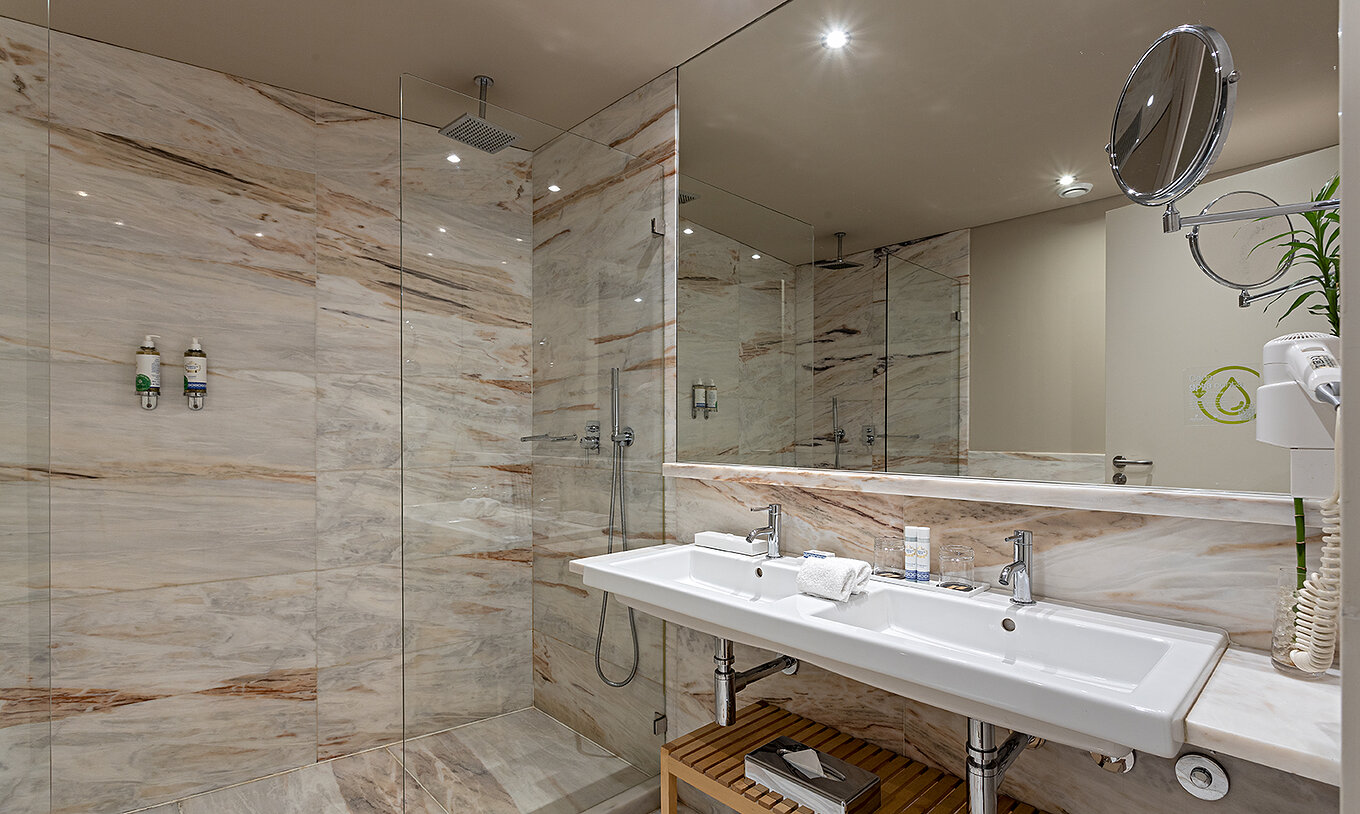 The Heritage Suite at Pestana Vintage Porto has a bathroom with marble walls, sink and shower