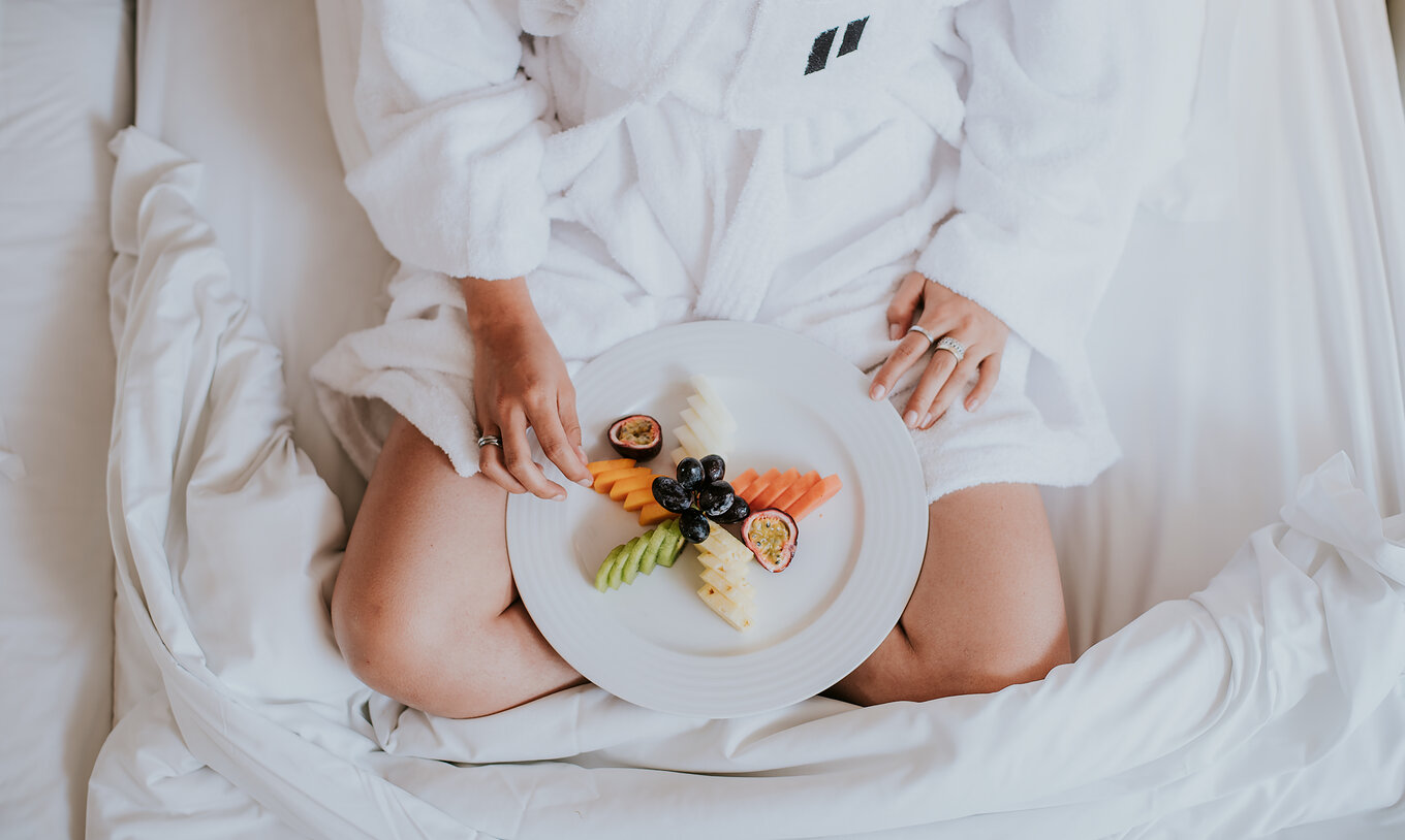 The Classic room at Pestana Miramar São Tomé offers breakfast in the room, with a lady carrying a plate of sliced fresh fruit