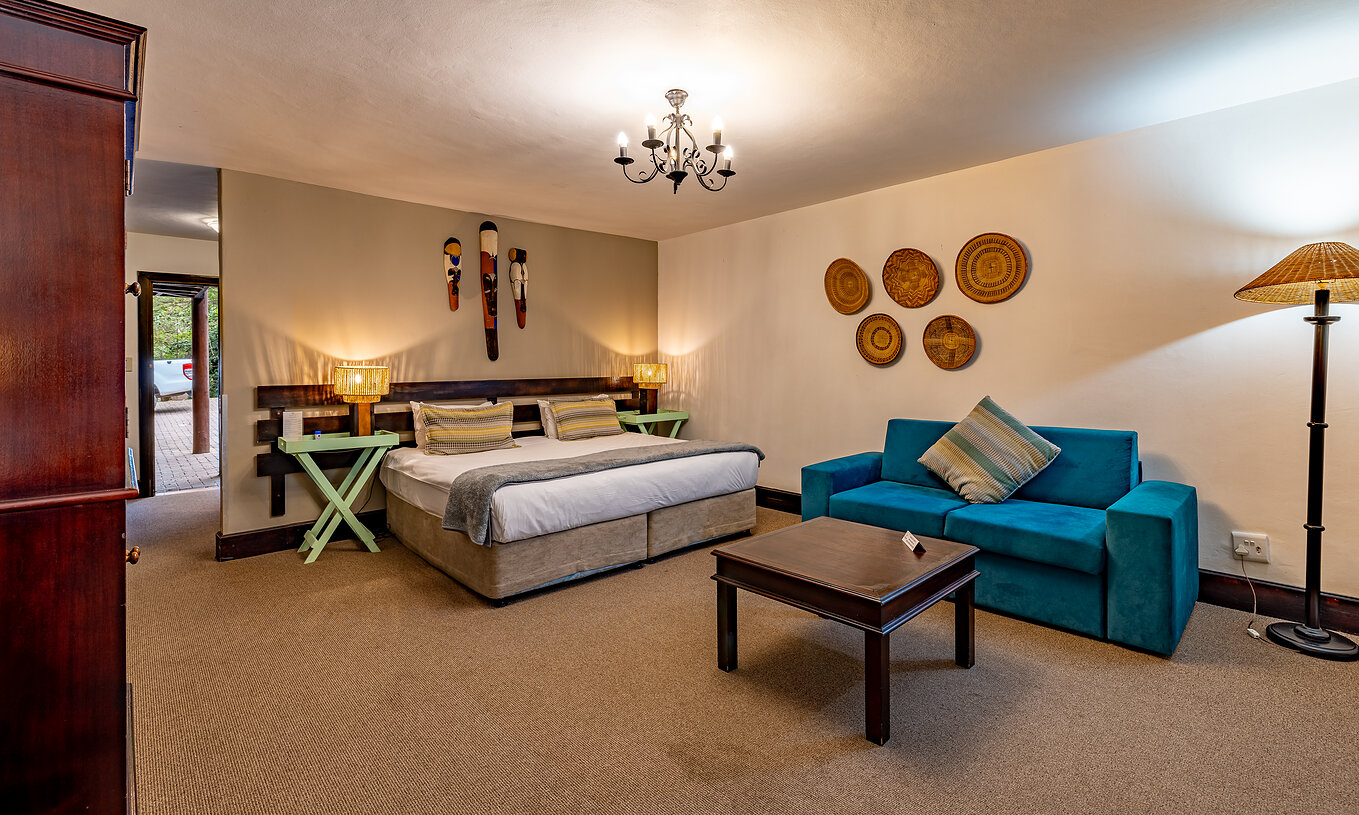The Premium Room at Pestana Kruger Lodge has a double bed, a blue sofa and typical African decor